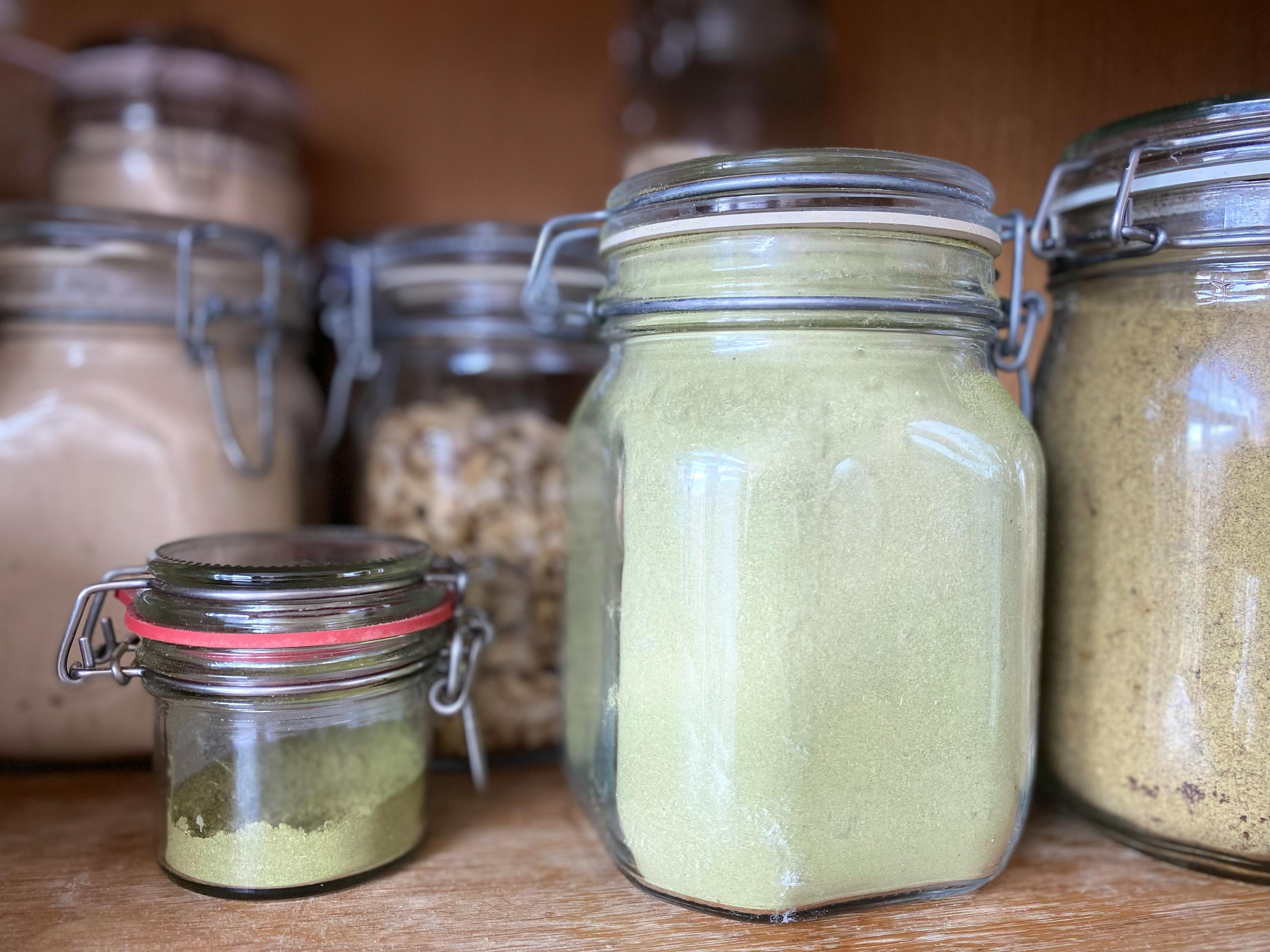deux bocaux en verre remplis de poudre verte sont assis sur une étagère