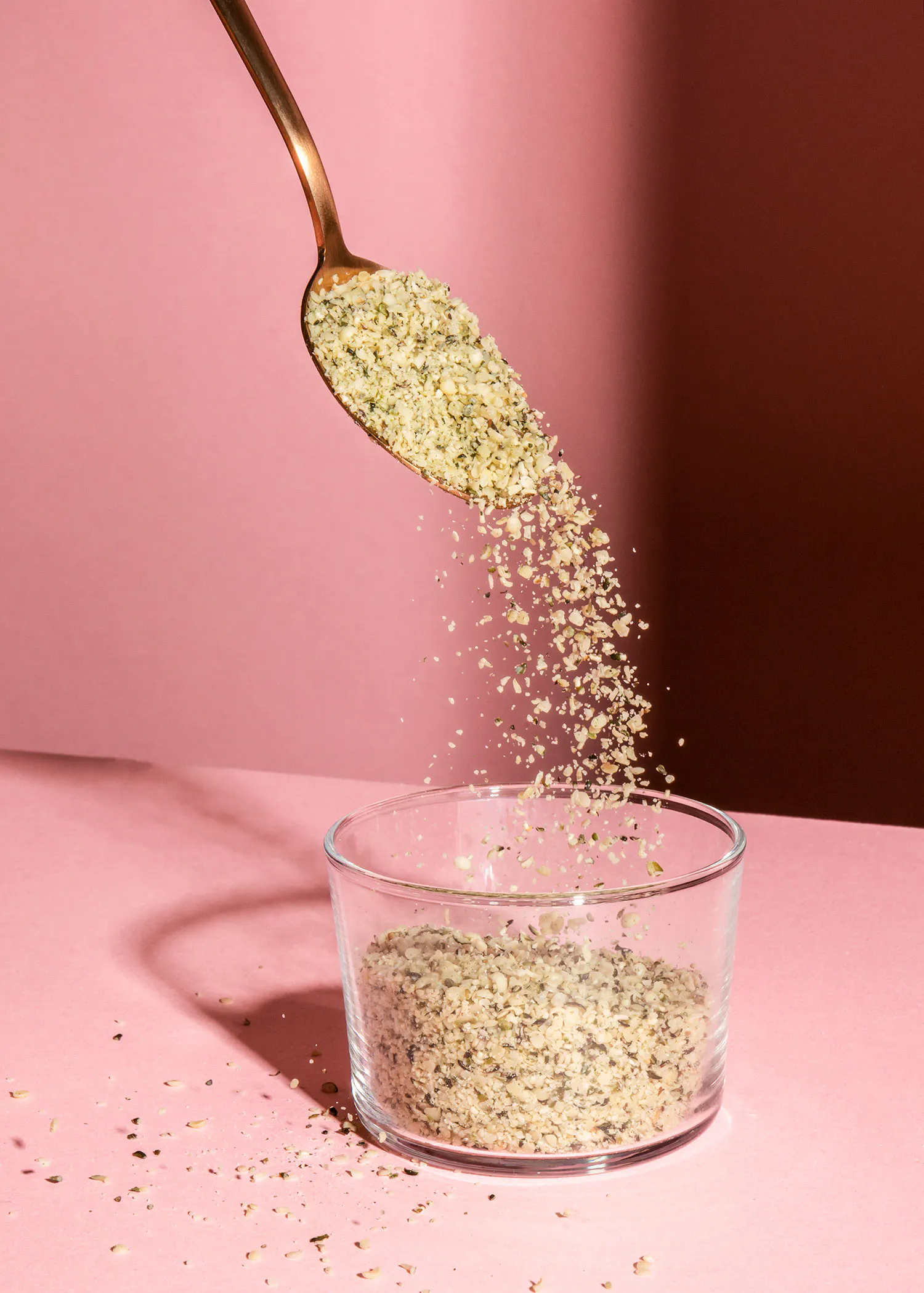 une cuillère de graines de chanvre est versée dans un bol en verre