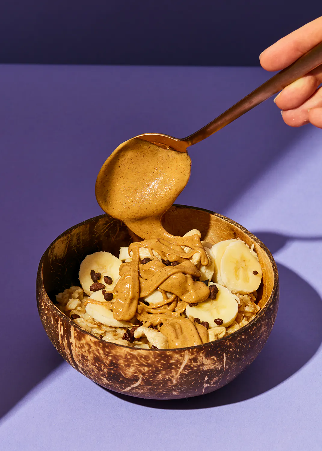 eine Person gießt Erdnussbutter in eine Schüssel Müsli