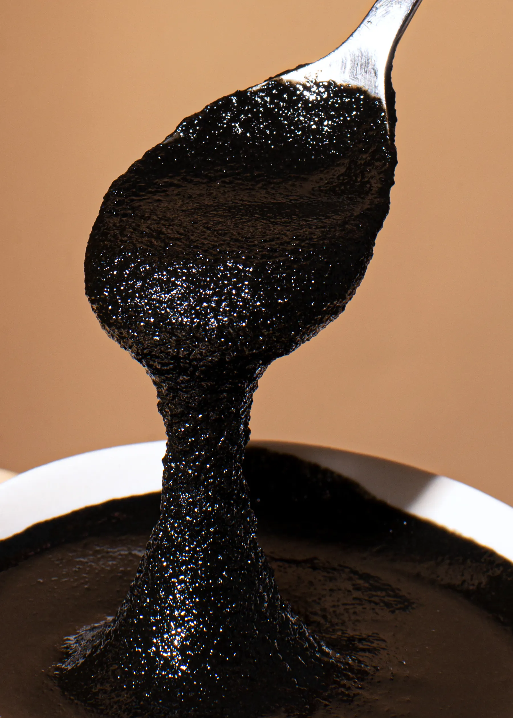 une cuillère remplie de sauce noire sort d' un bol