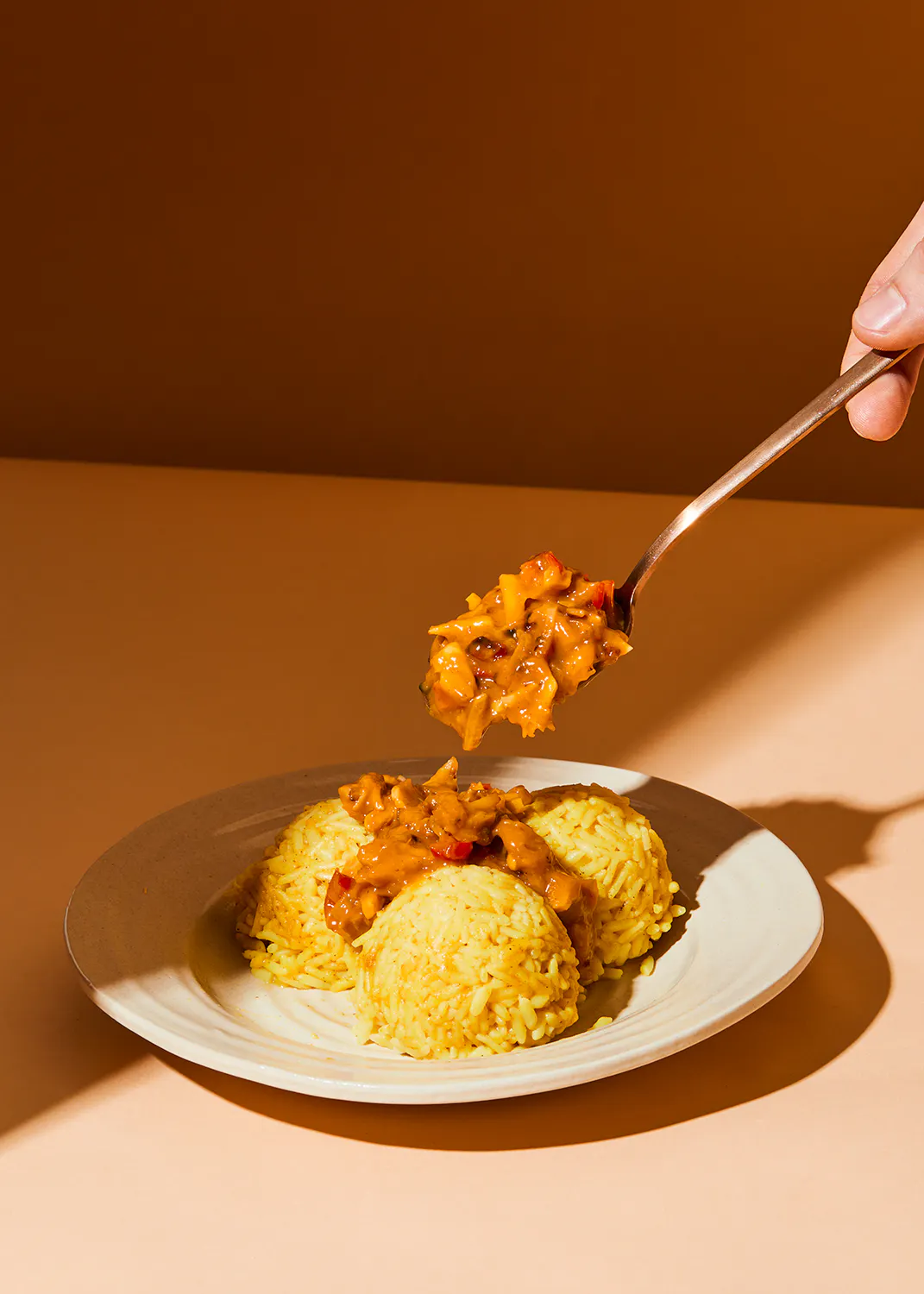 une personne tient une cuillère dessus d' une assiette de nourriture