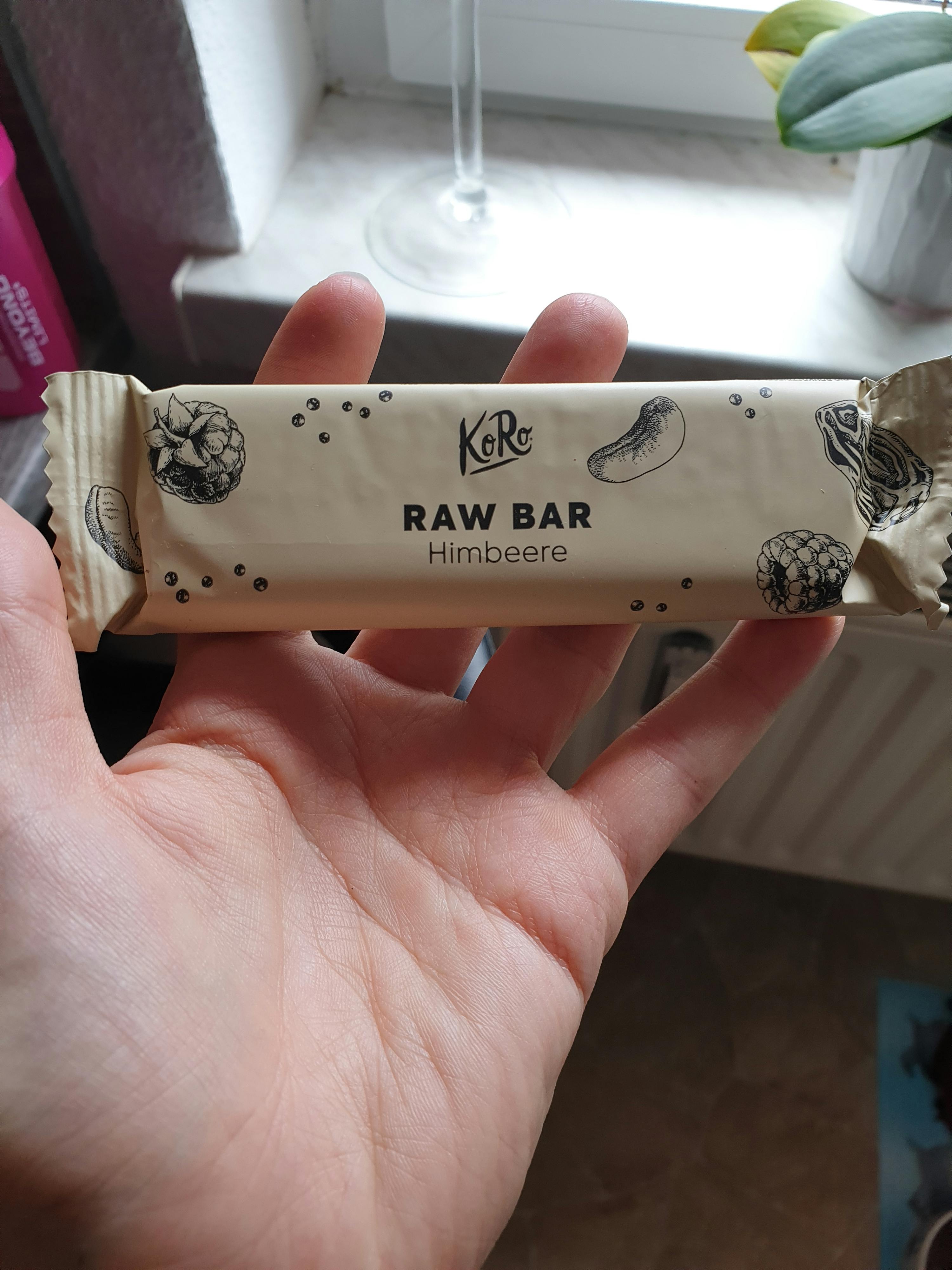 una persona tiene in mano una barretta di cioccolato raw