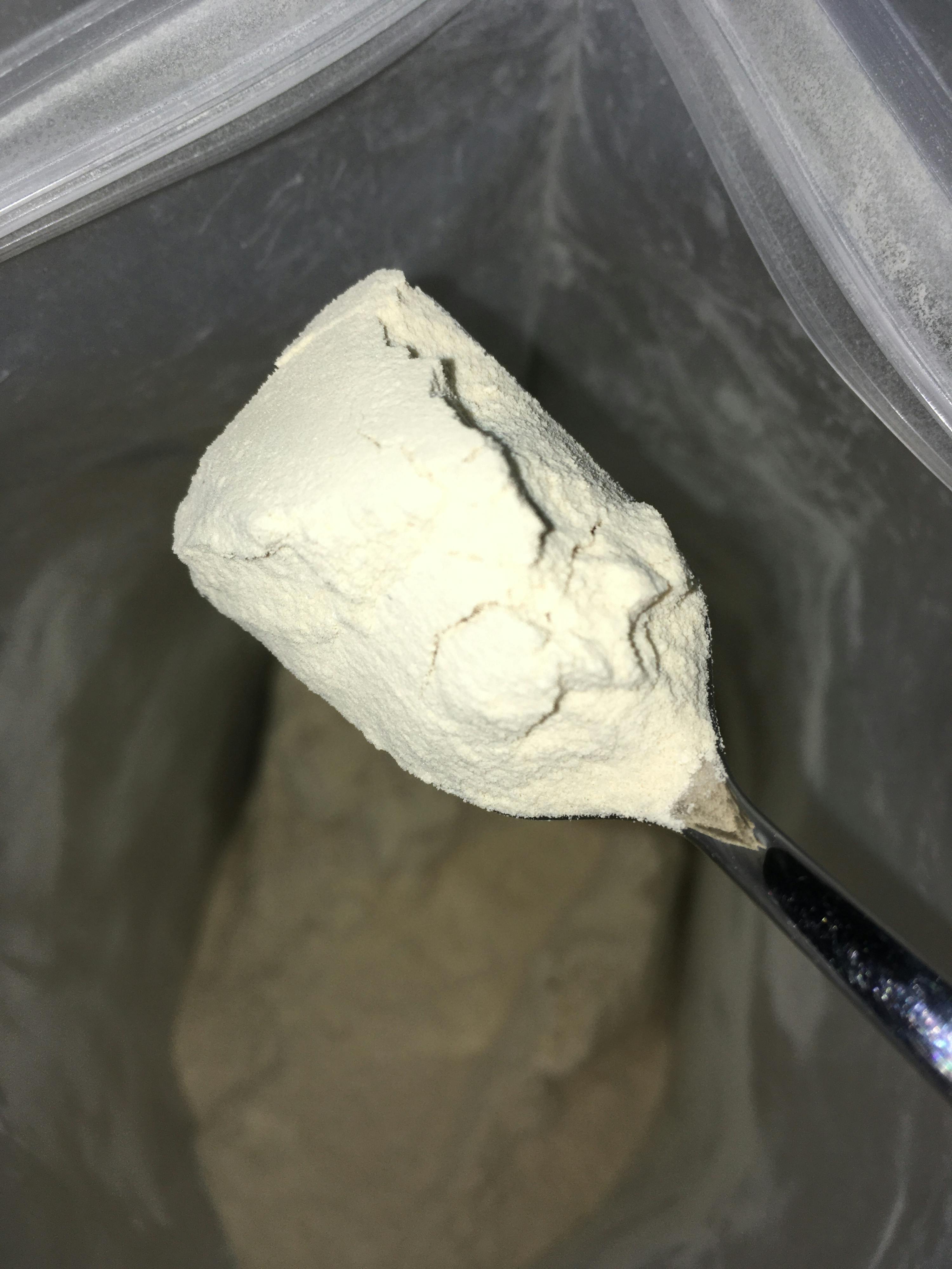 a spoonful of white powder is being poured into a plastic bag