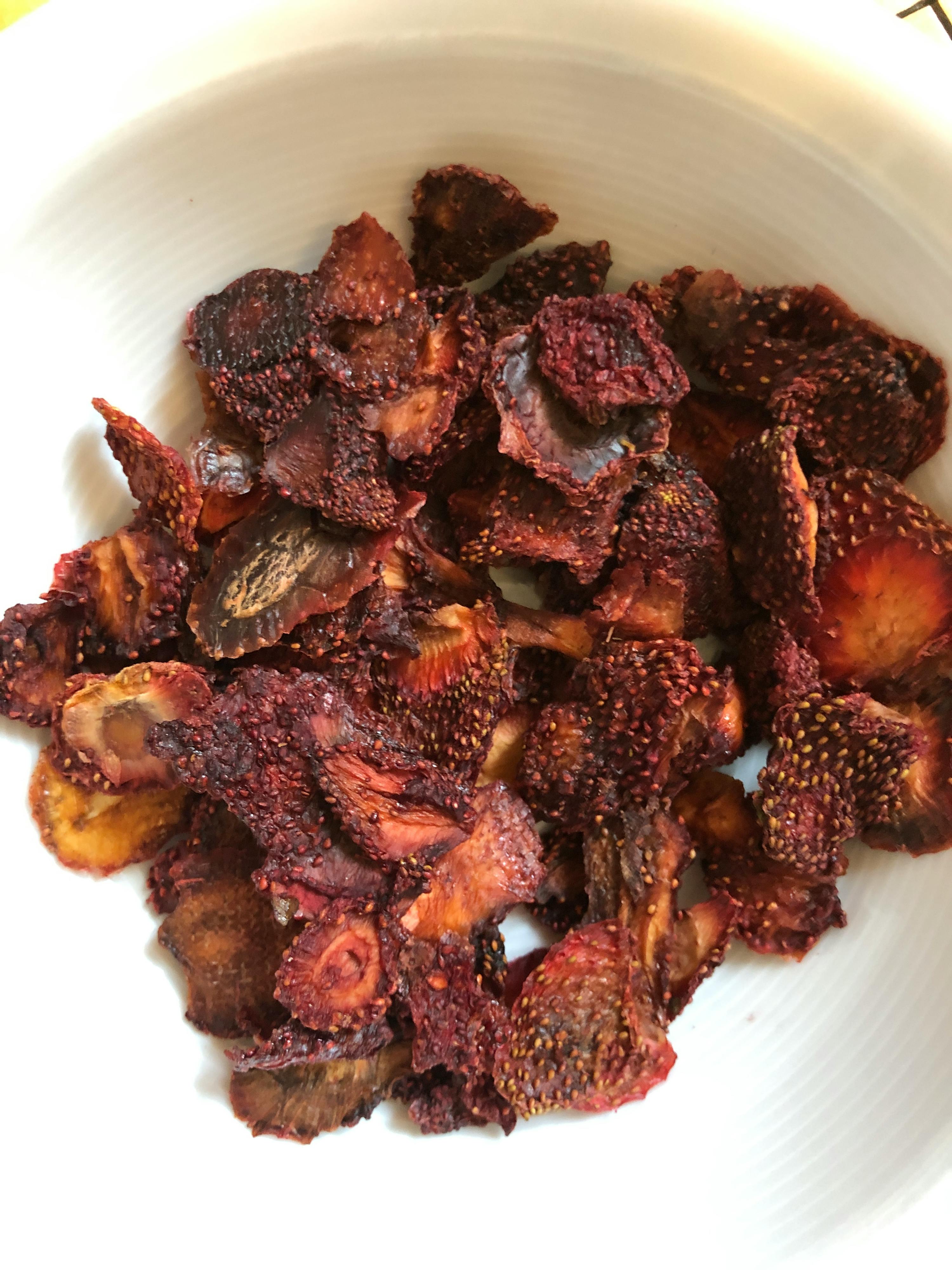 a white bowl filled with a pile of dried strawberries