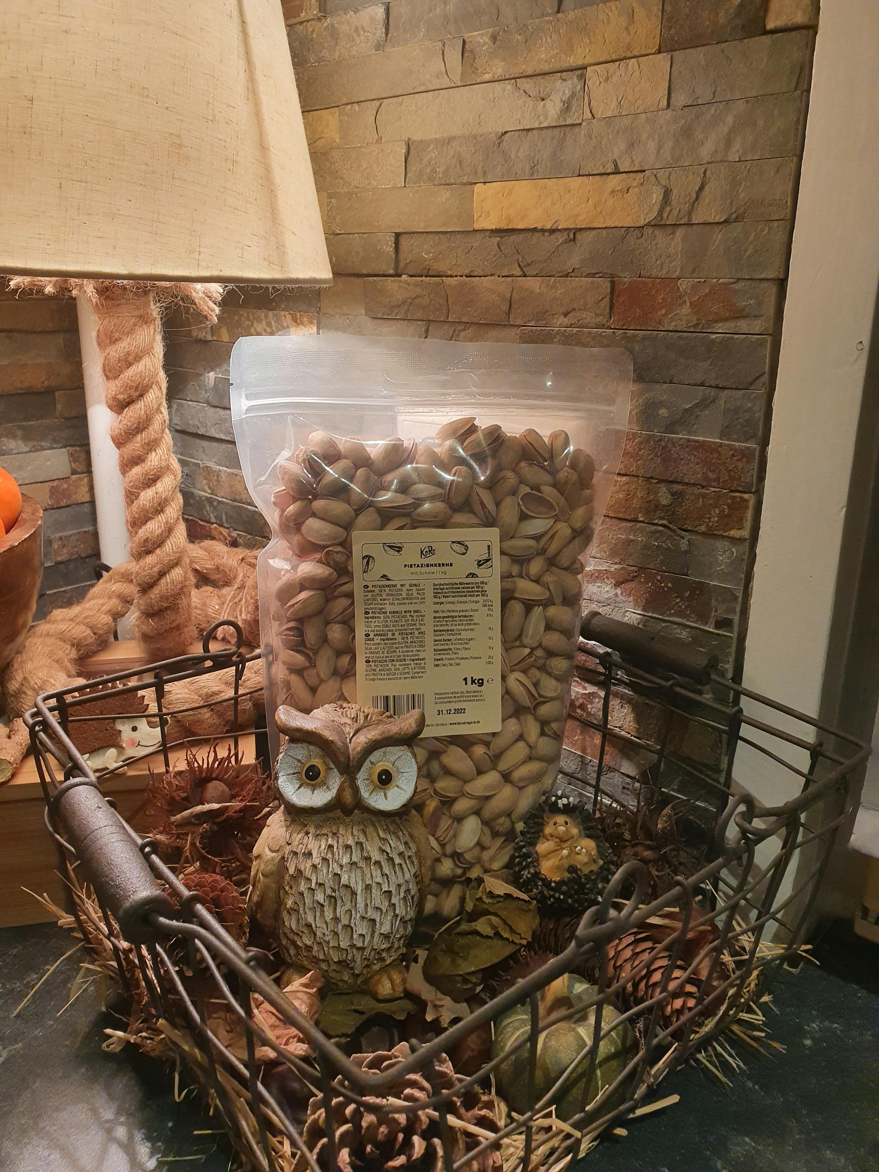 a bag of pistachios sits on a table next to an owl figurine