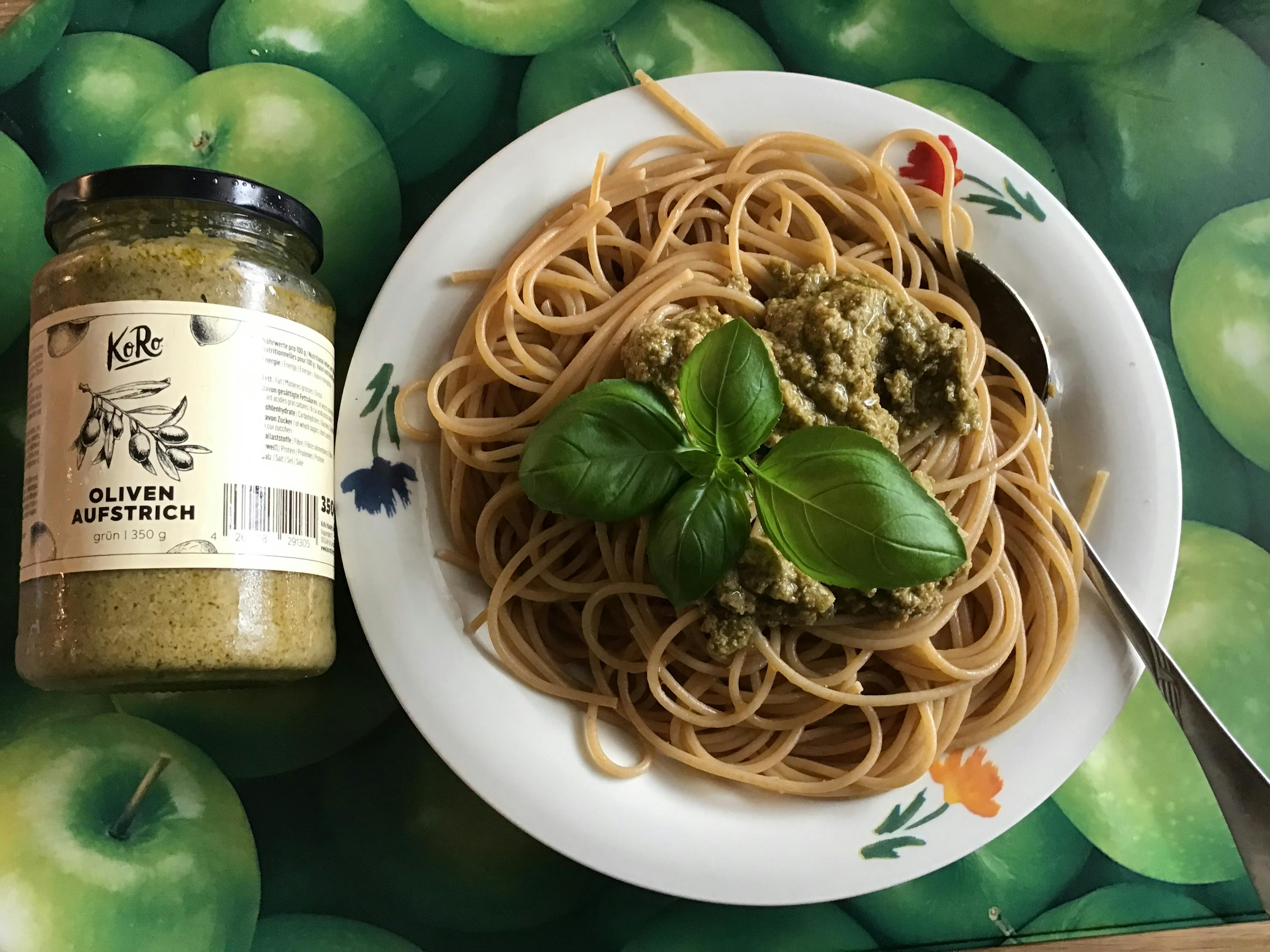 a plate of spaghetti next to a jar of oliven aufstrich