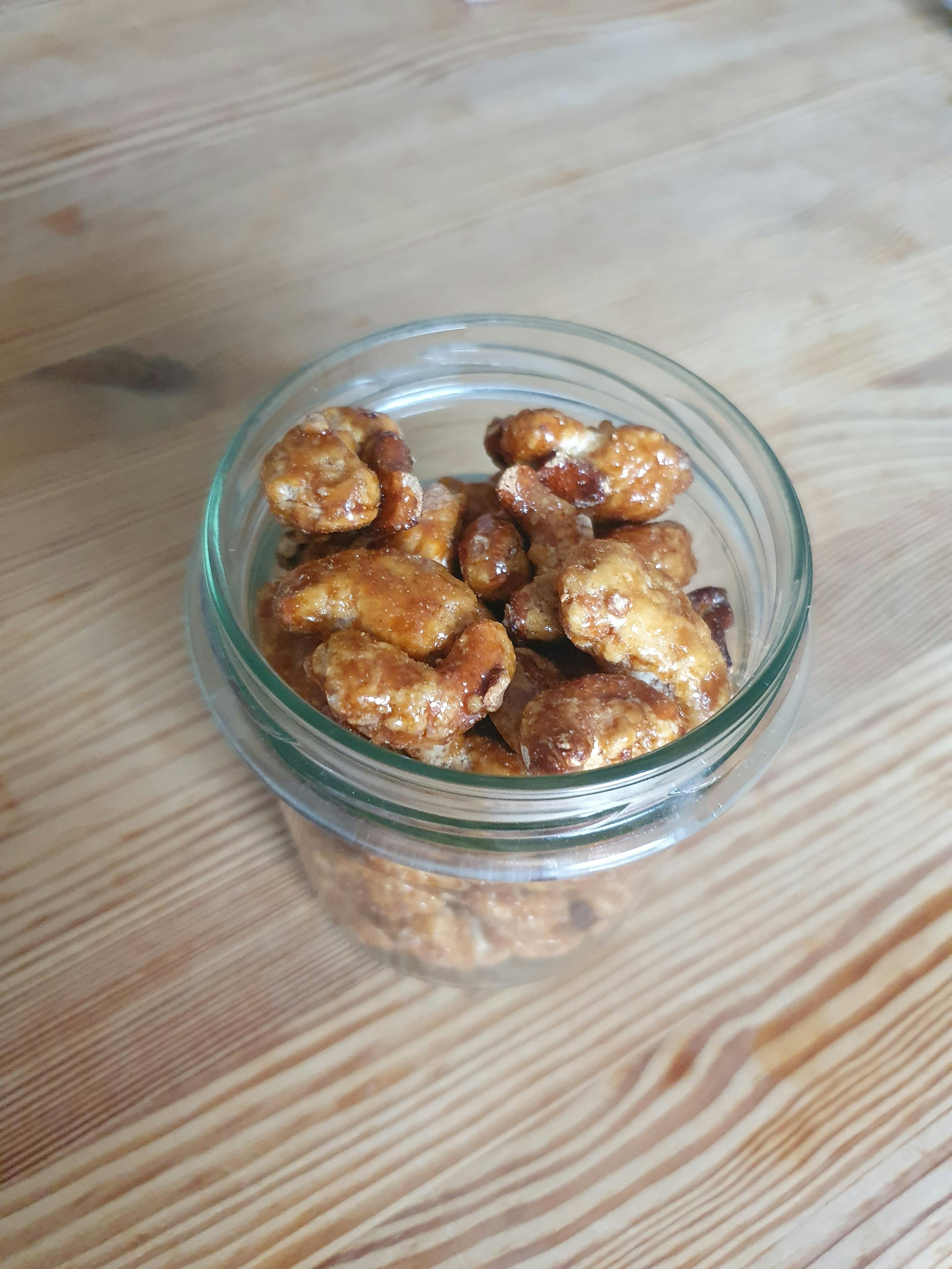 un bocal rempli de noix caramélisées sur une table en bois