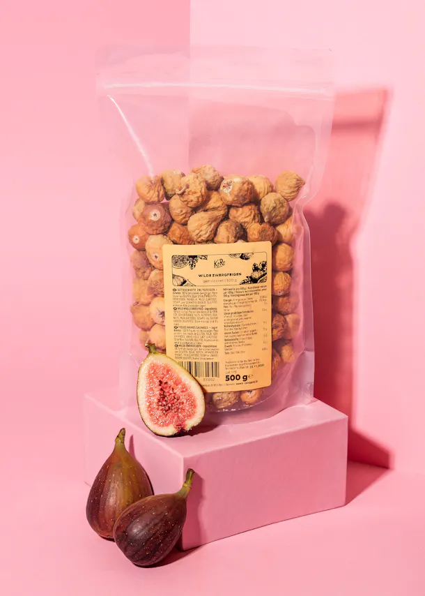 a bag of figs sits on a pink box
