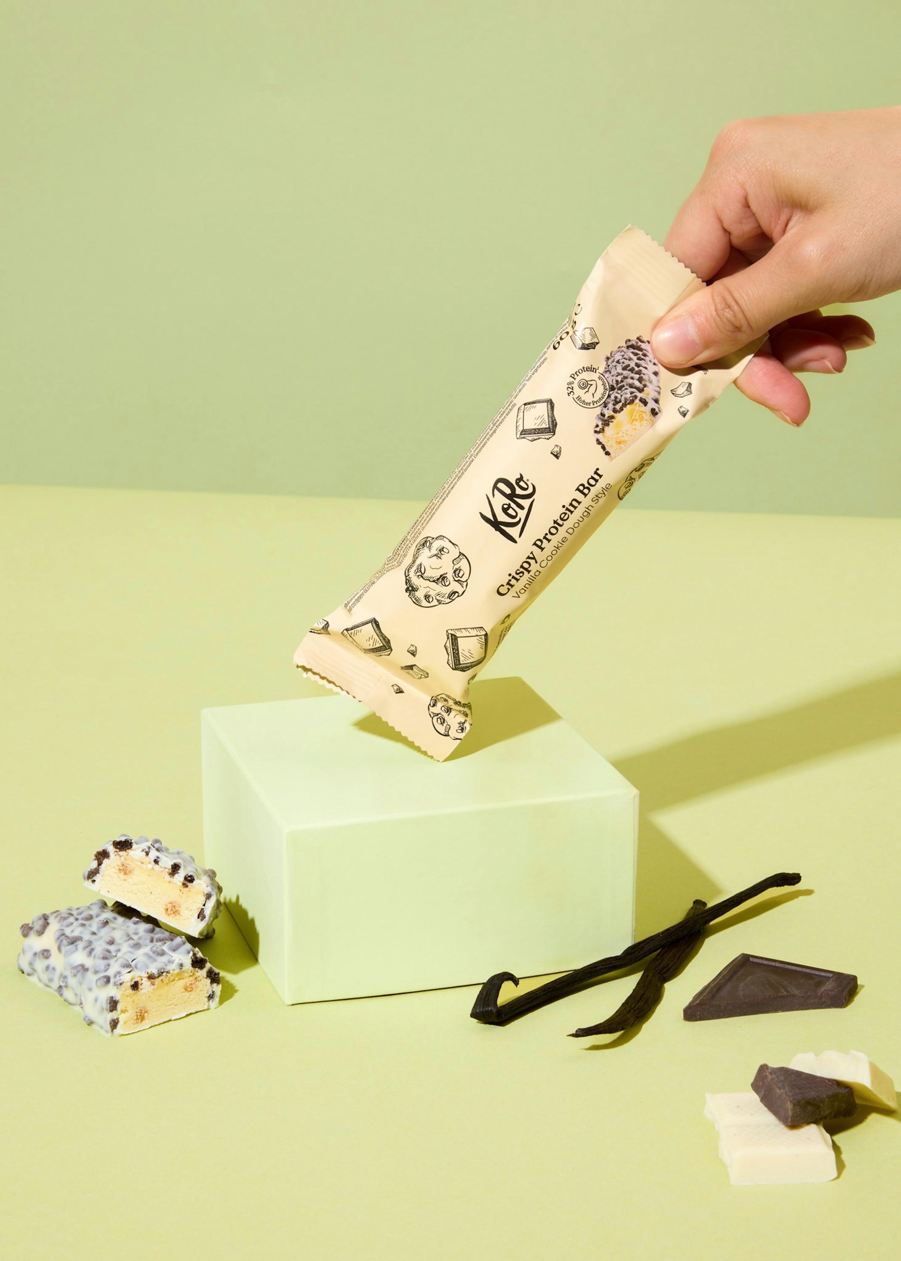 une personne tient une barre de proteine croustillante à la vanille