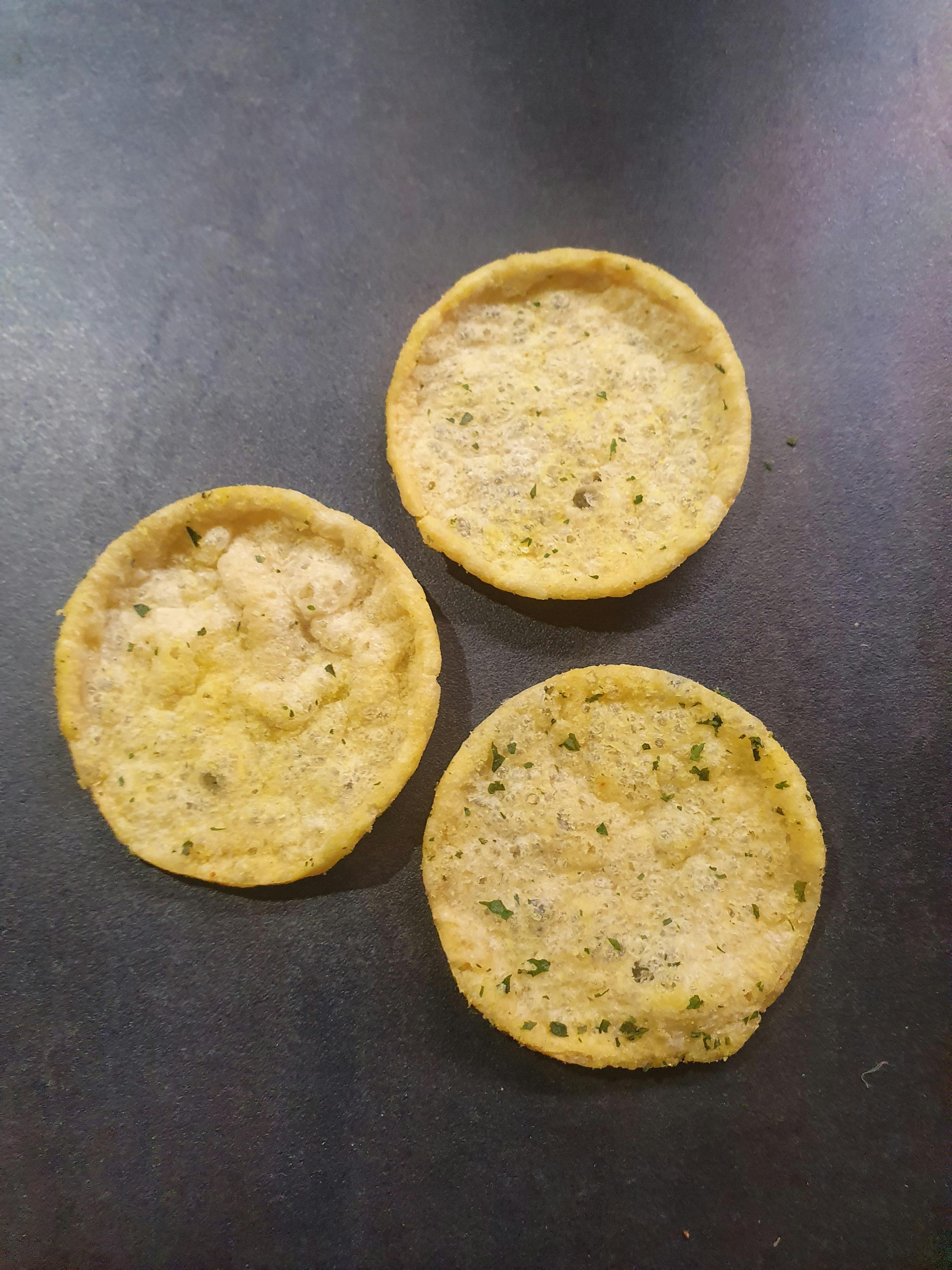 three tortilla chips are on a black surface