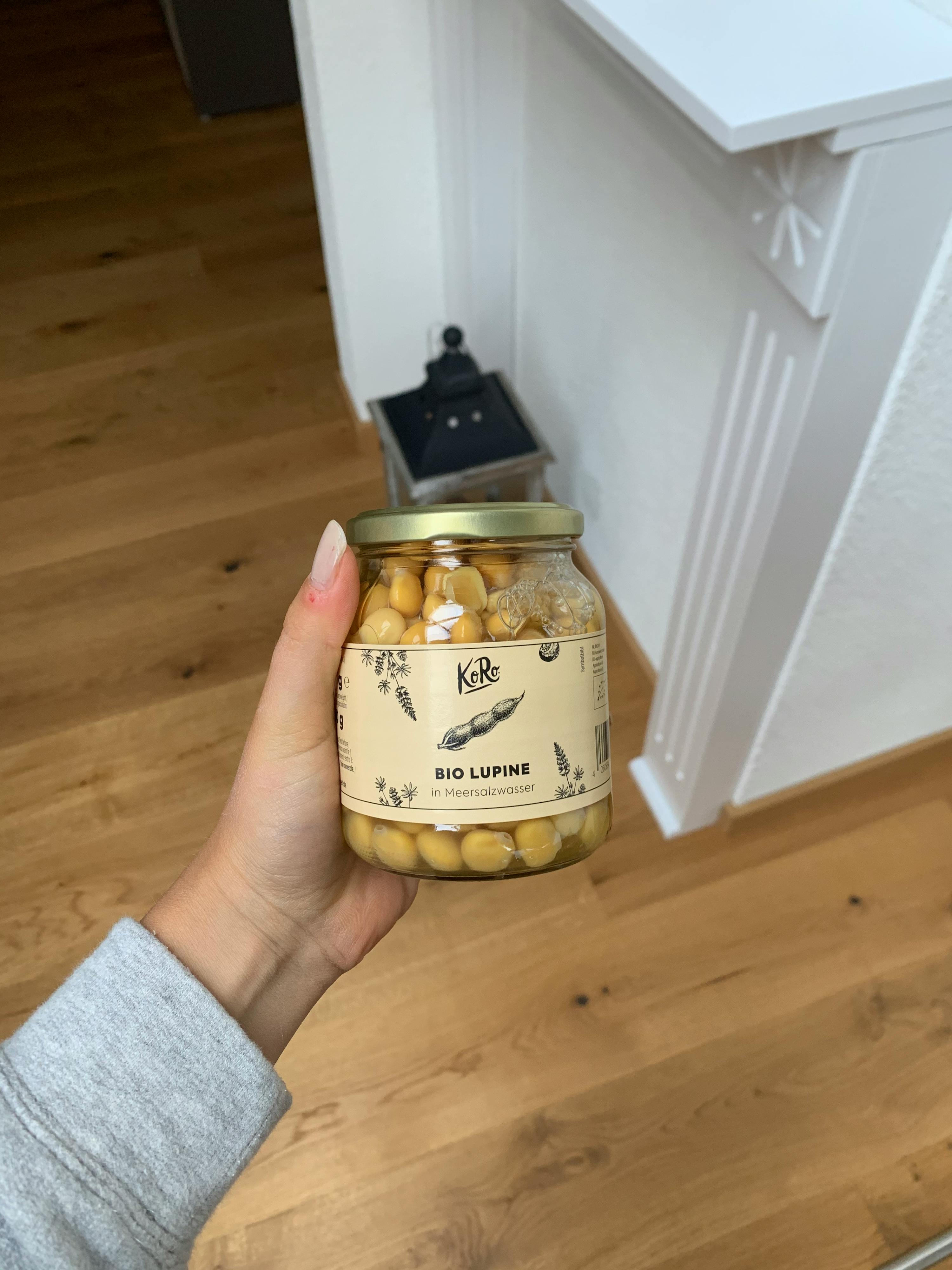 une personne tient un bocal de lupins bio dans sa main