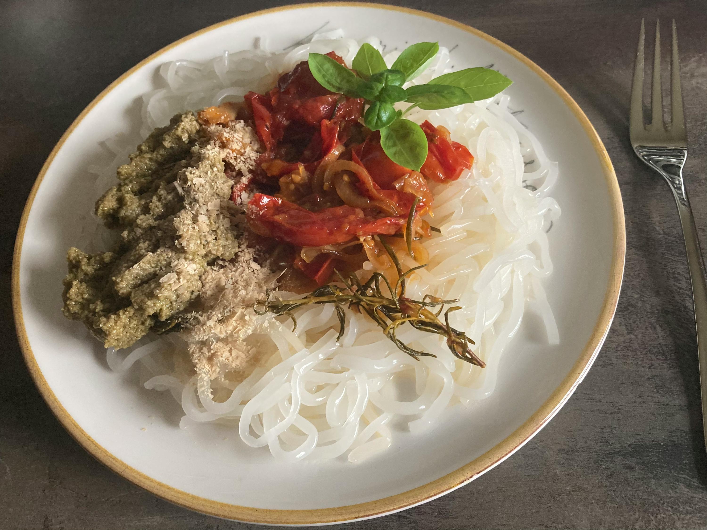 a plate of food with noodles and vegetables next to a fork