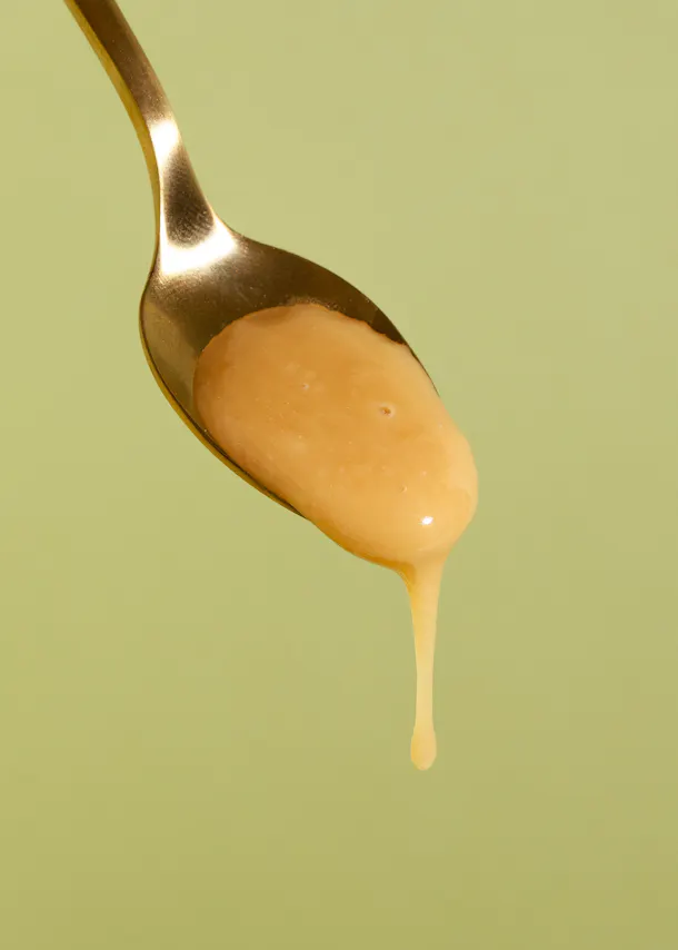 une cuillère remplie de sauce avec une goutte qui sort de la cuillère