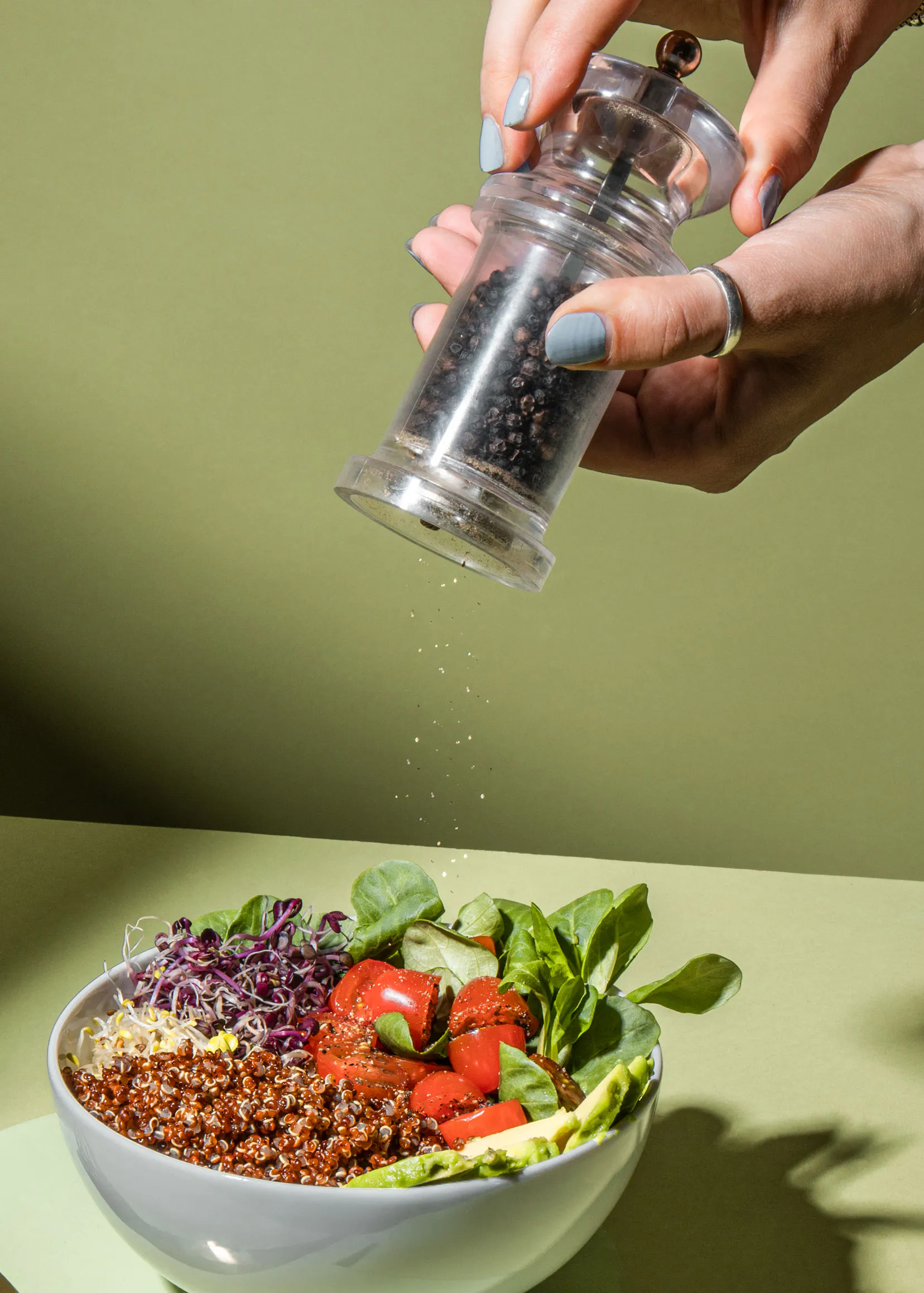 une personne verse du poivre sur un bol de nourriture