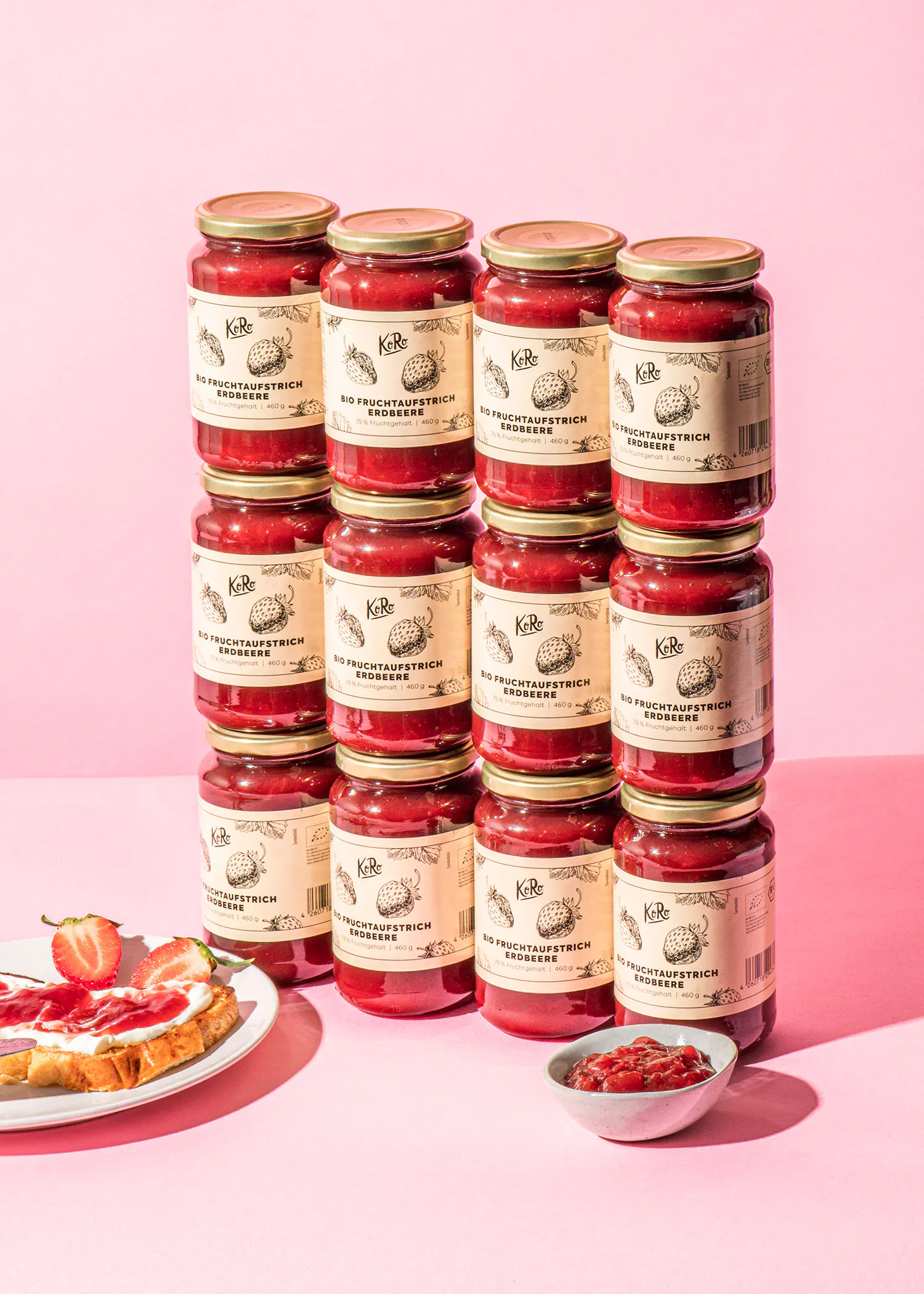 eine Reihe von Gläsern mit Erdbeermarmelade auf einem rosa Hintergrund