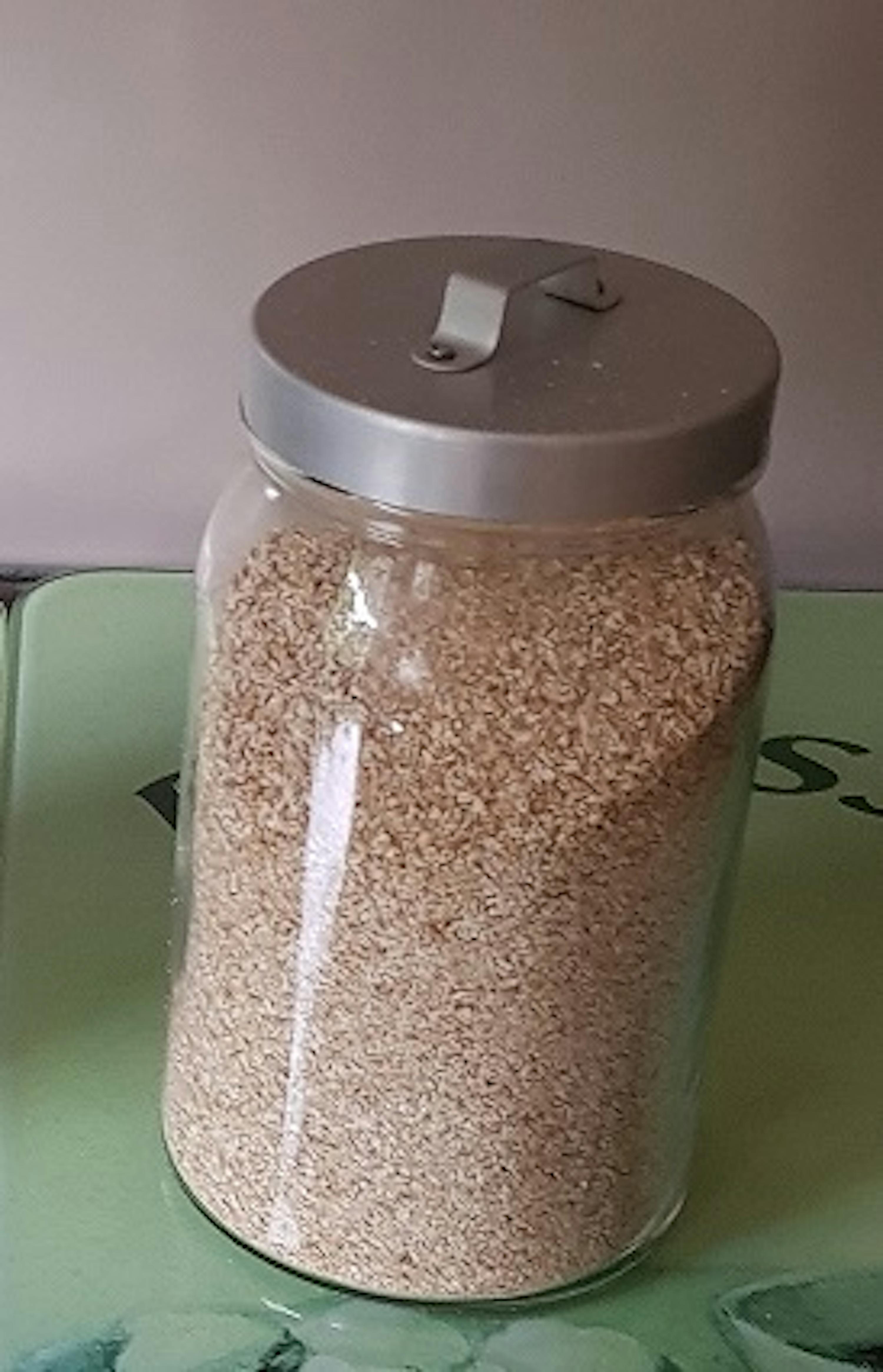 Ein Glasgefäß voller Haferflocken steht auf einem Tisch .