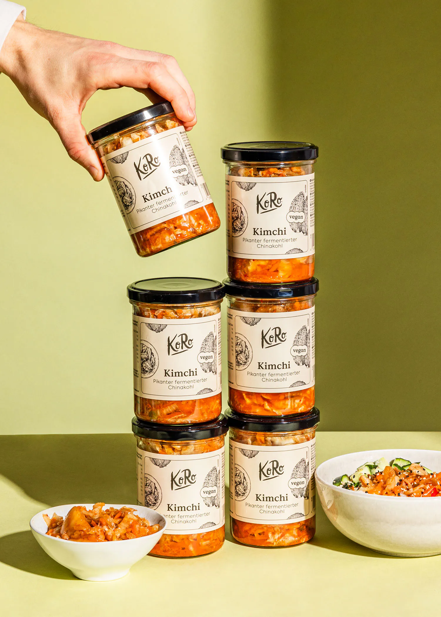 eine Person stapelt Kimchi-Gläser aufeinander und hält einen Kimchi-Gläser in der Hand