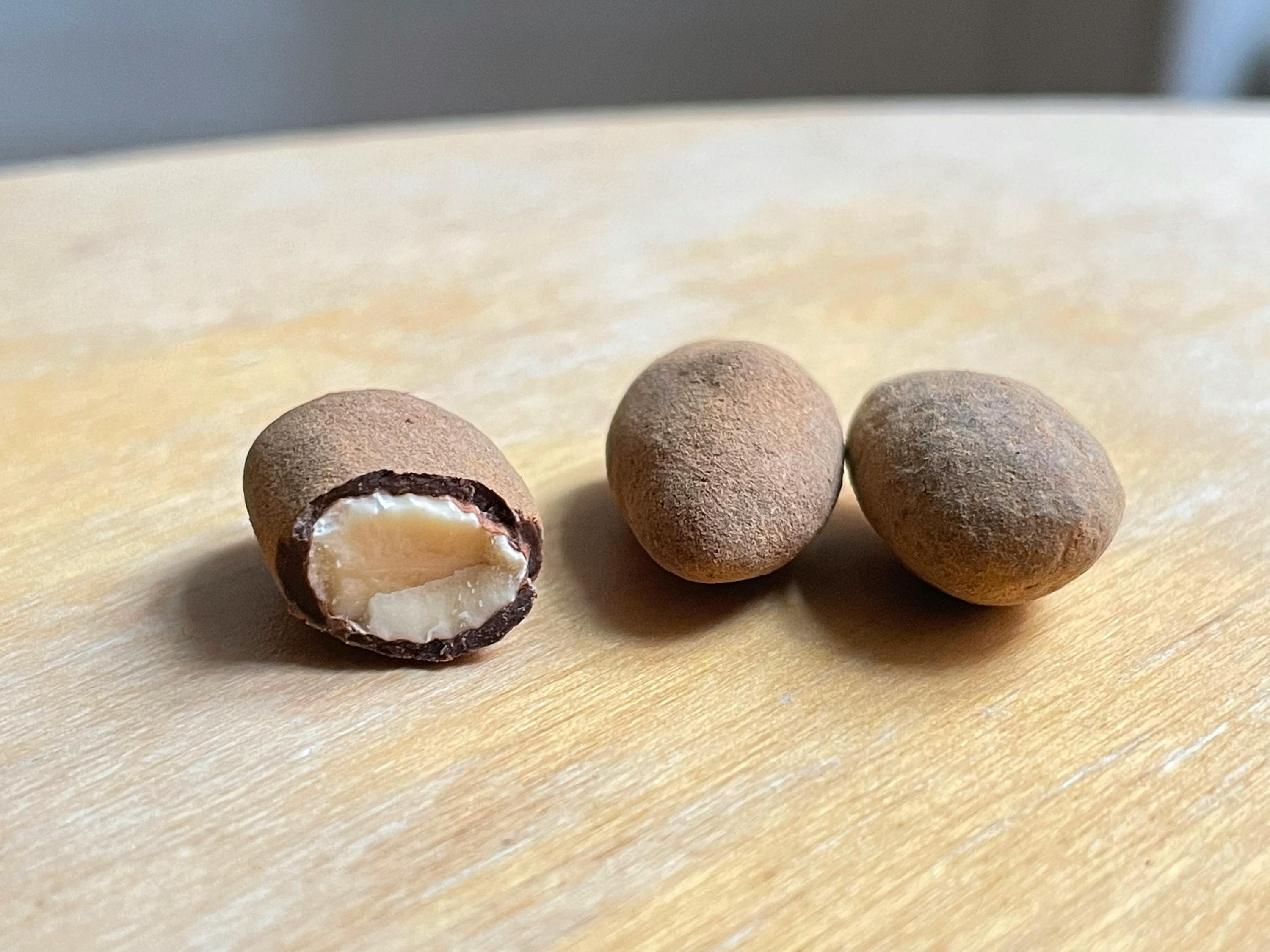 drei Erdnüsse auf einem Holztisch mit einer halbierten Erdnuss