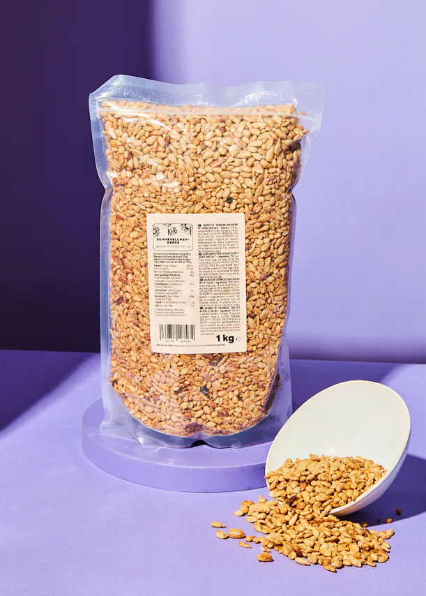 un sac de graines de sésame est assis sur une table violette à côté d' une cuillère