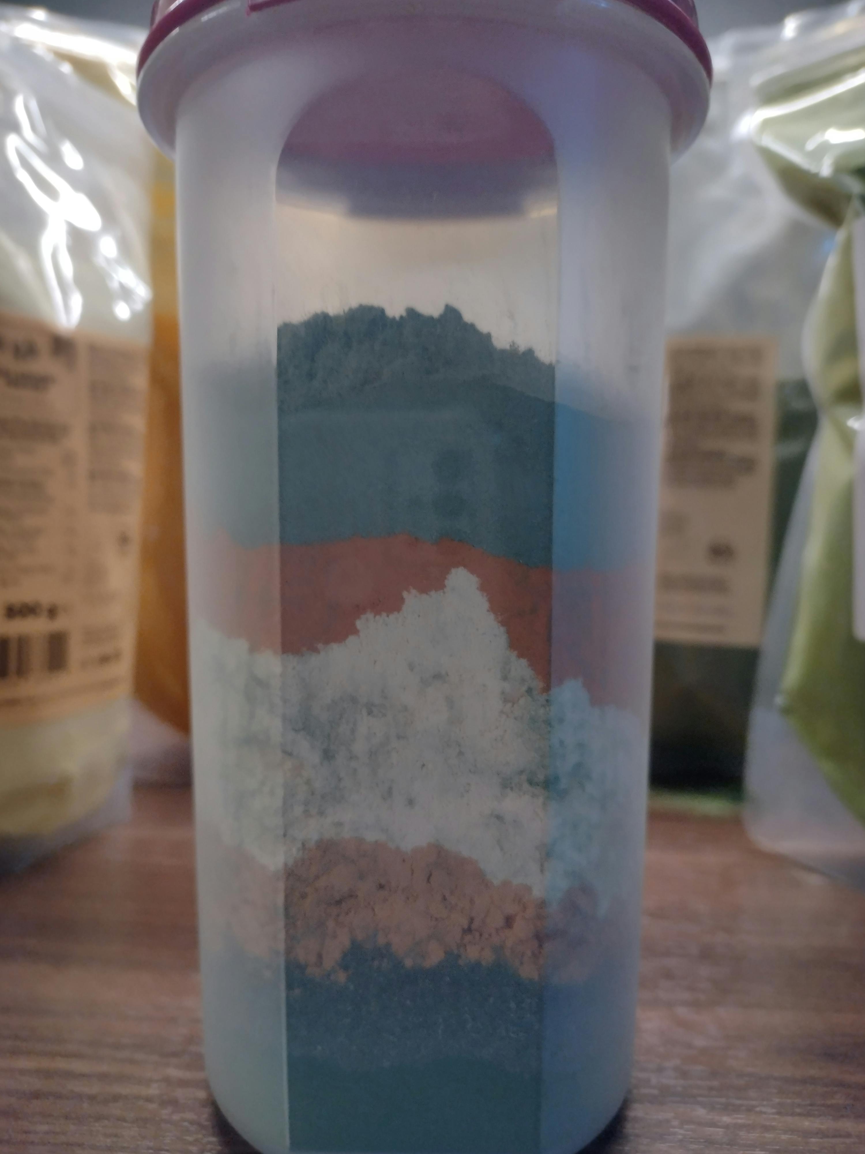 a clear container filled with different colored powders