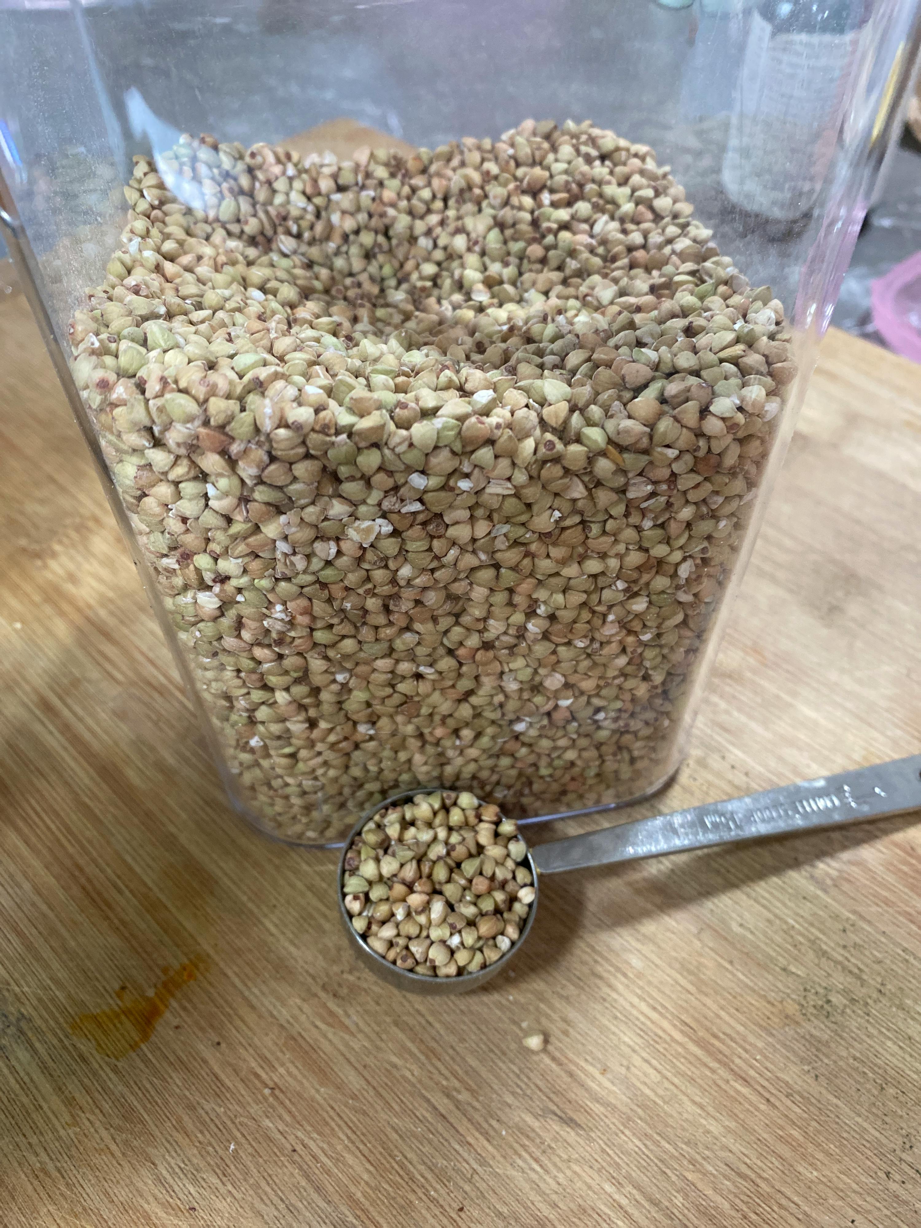 a measuring spoon sits next to a jar of buckwheat