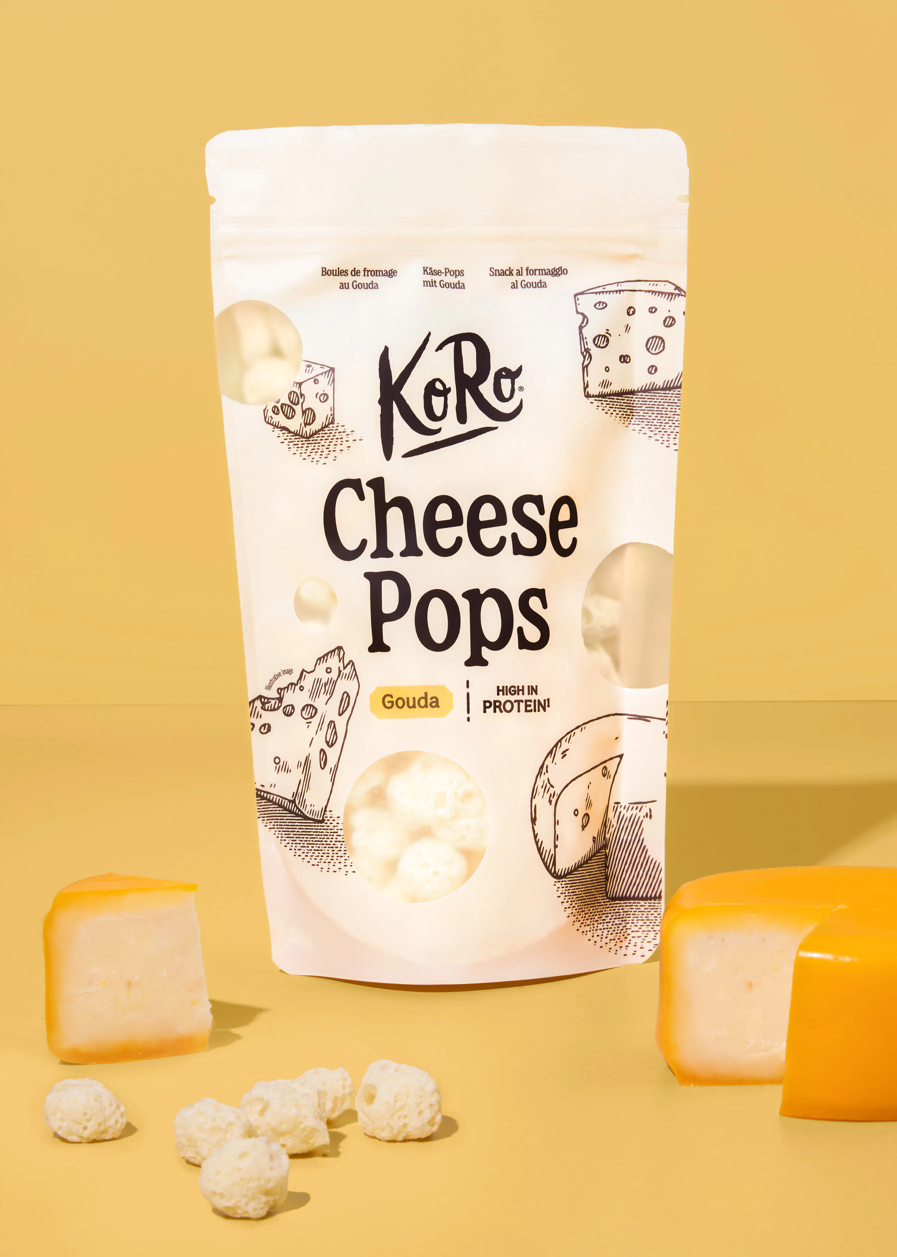 confezione di koro cheese pops al gouda circondata da pezzi di formaggio gouda e snack croccanti su sfondo giallo.