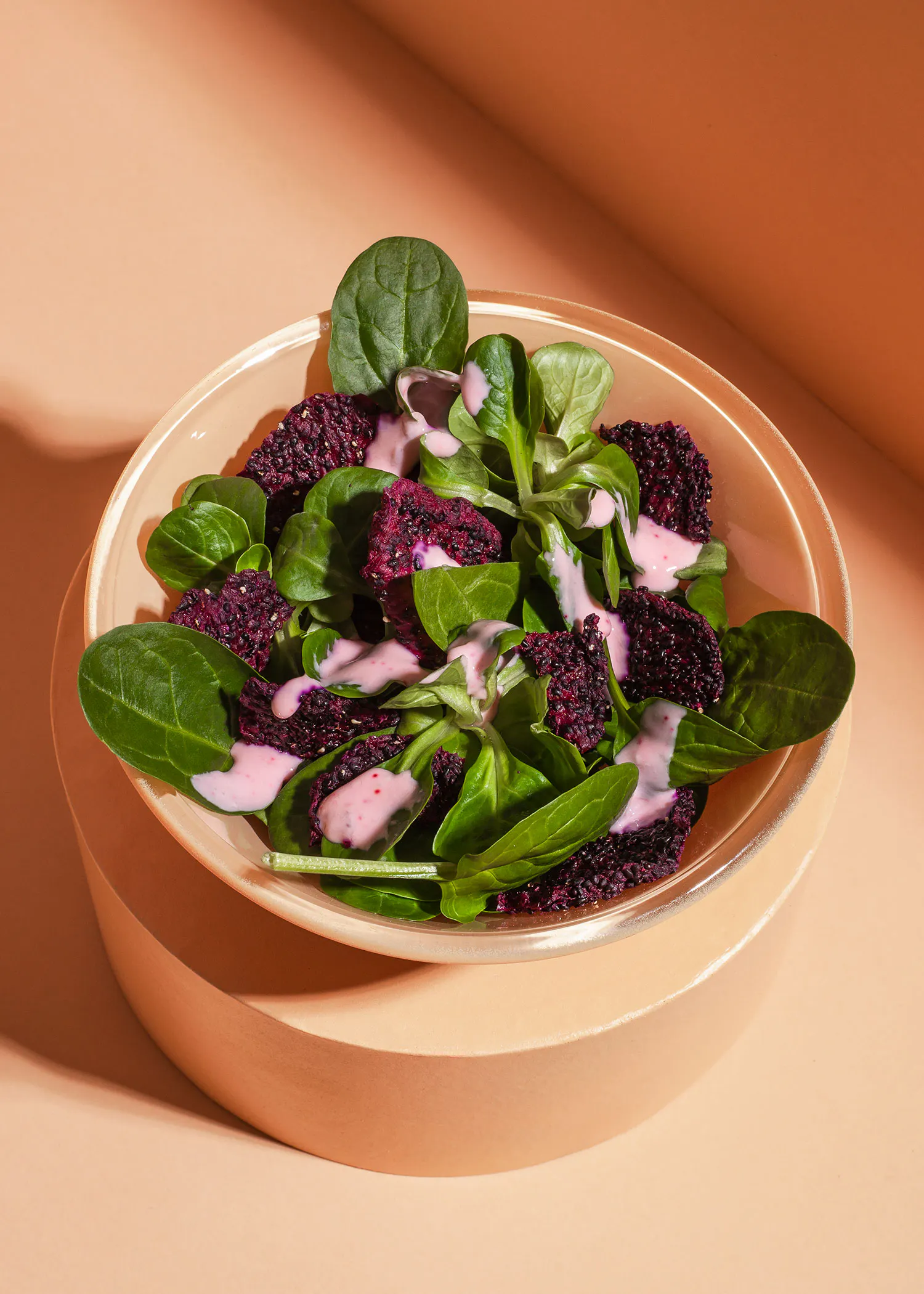 eine Schüssel mit einem Salat mit Spinat und einem rosa Soße