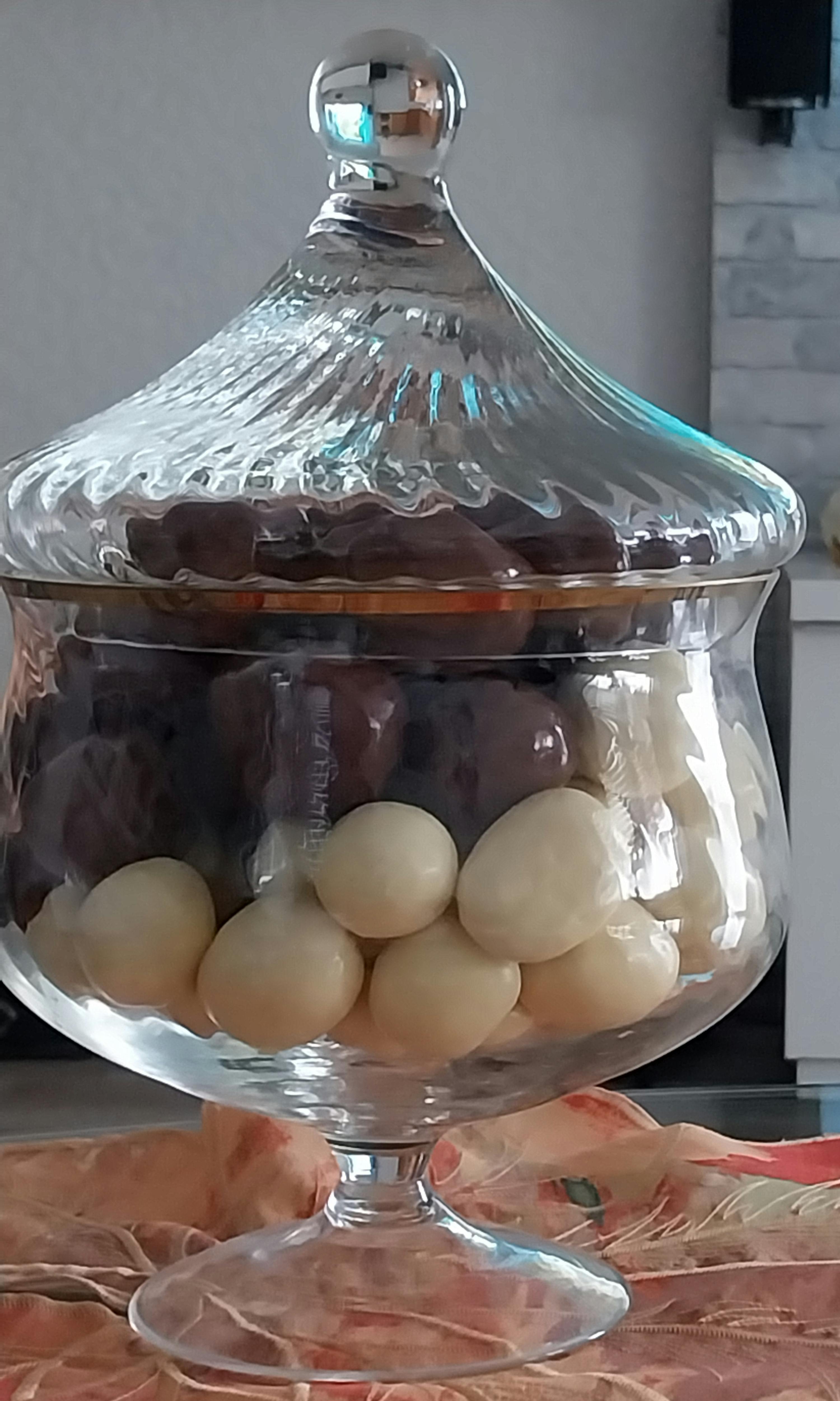 a clear glass container filled with nuts and a silver lid