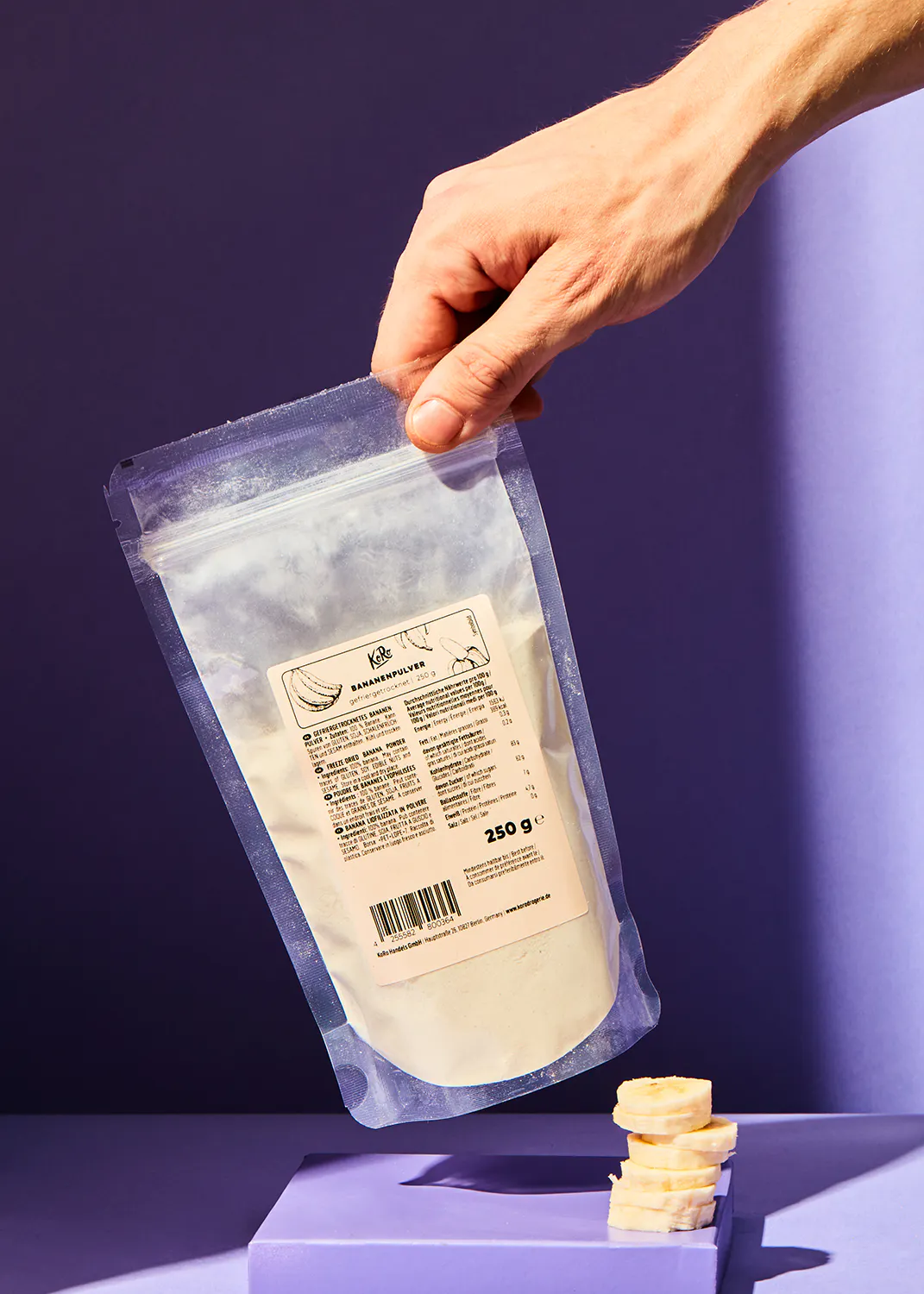 une personne tient un sac de poudre de banane 250 g