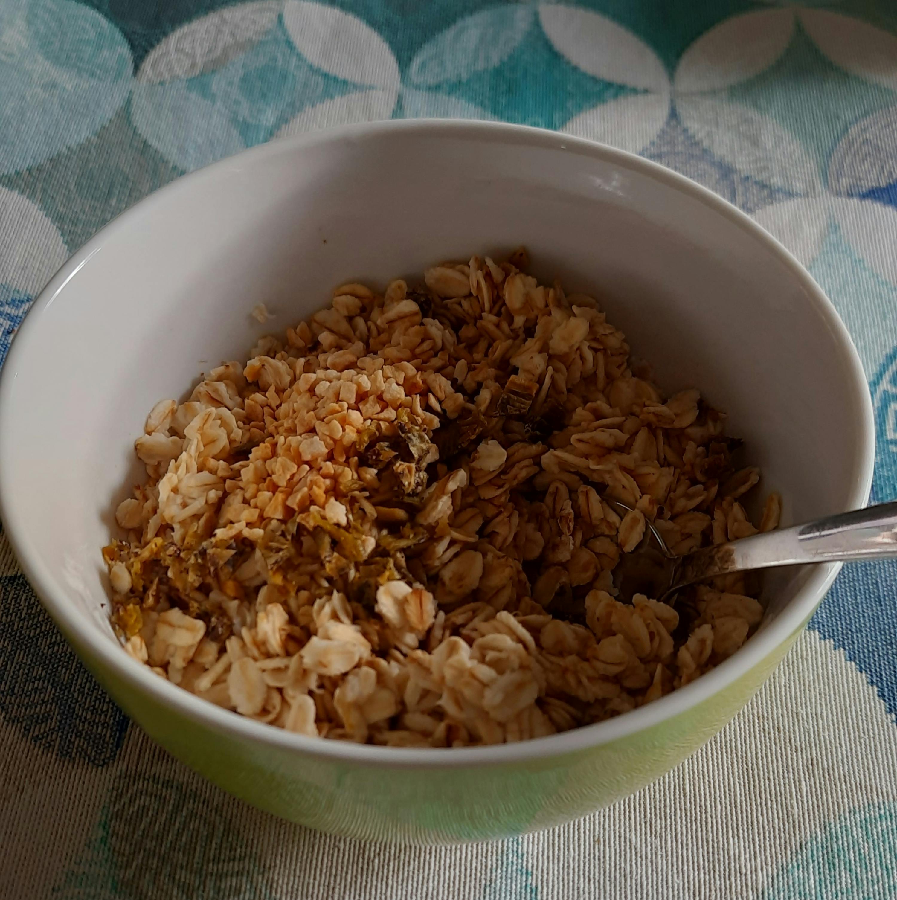 a green bowl of granola with a spoon in it