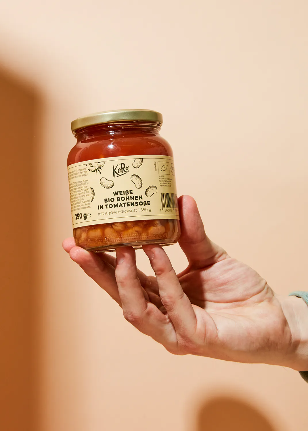 eine Person hält in ihrer Hand ein Glas weide bio-Kidneybohnen in Tomatensoße