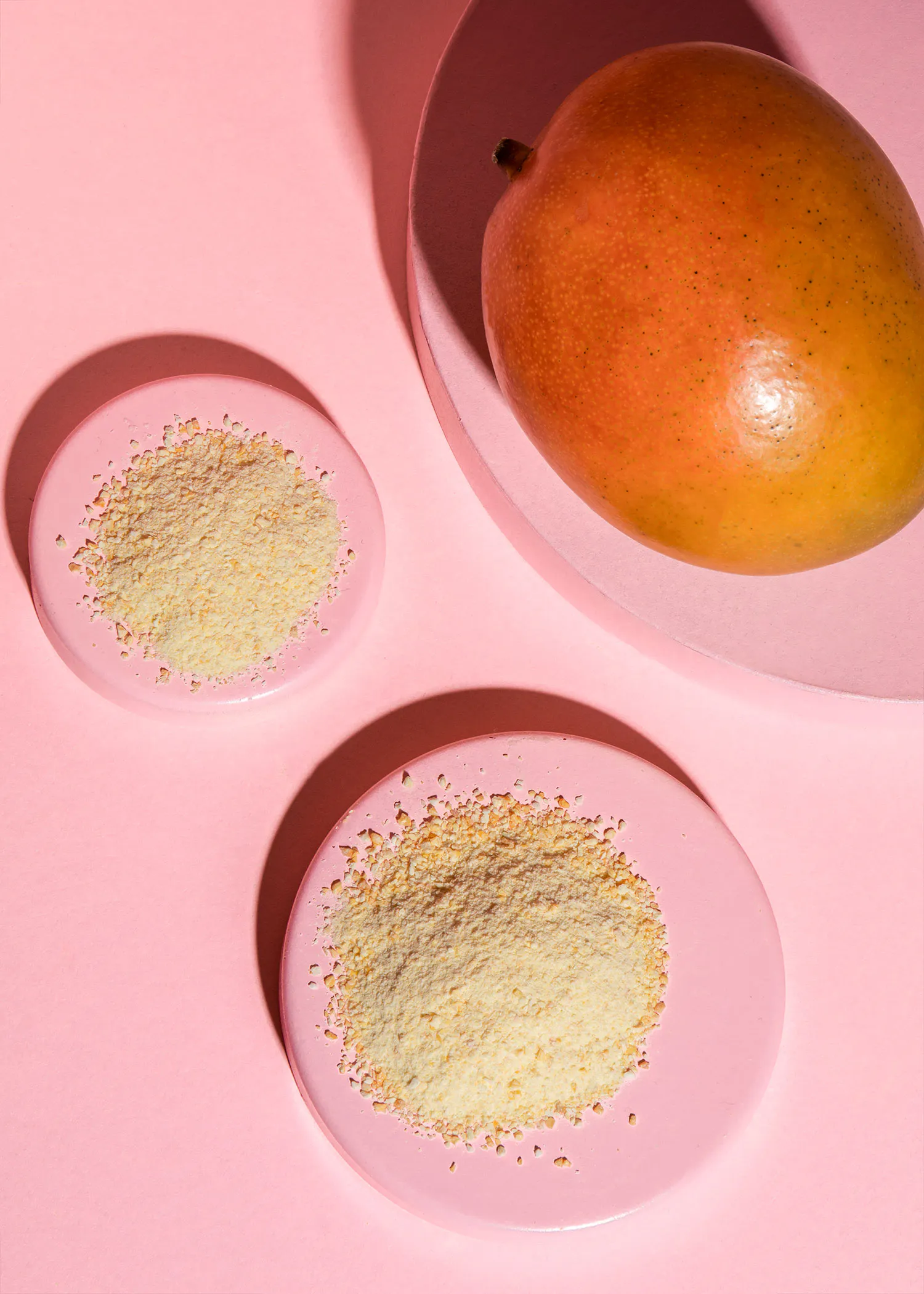 deux assiettes roses sont assises à côté d' une mangue sur une surface rose