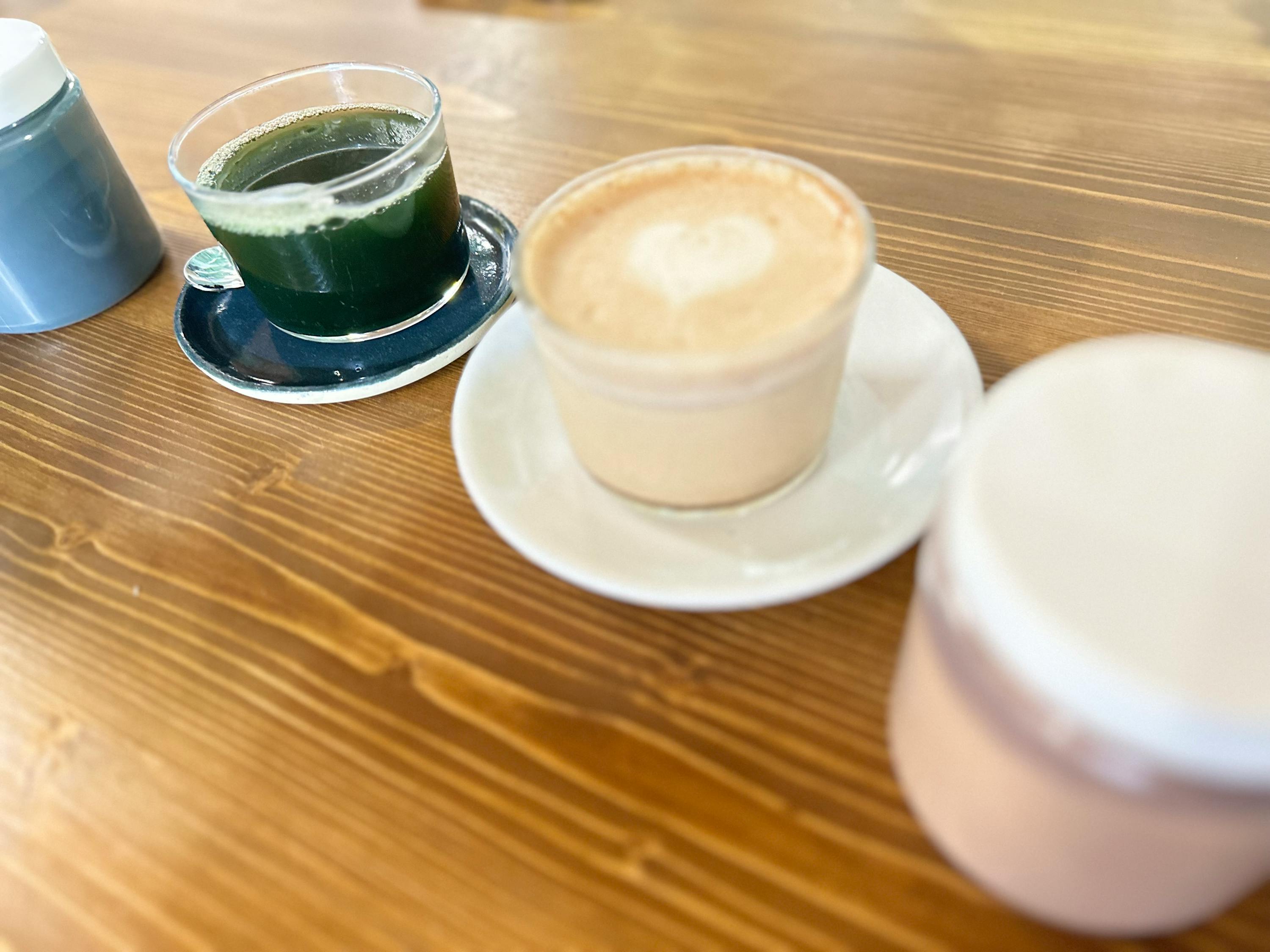 eine Tasse Kaffee auf einem Untersetzer neben einem grünen Getränk