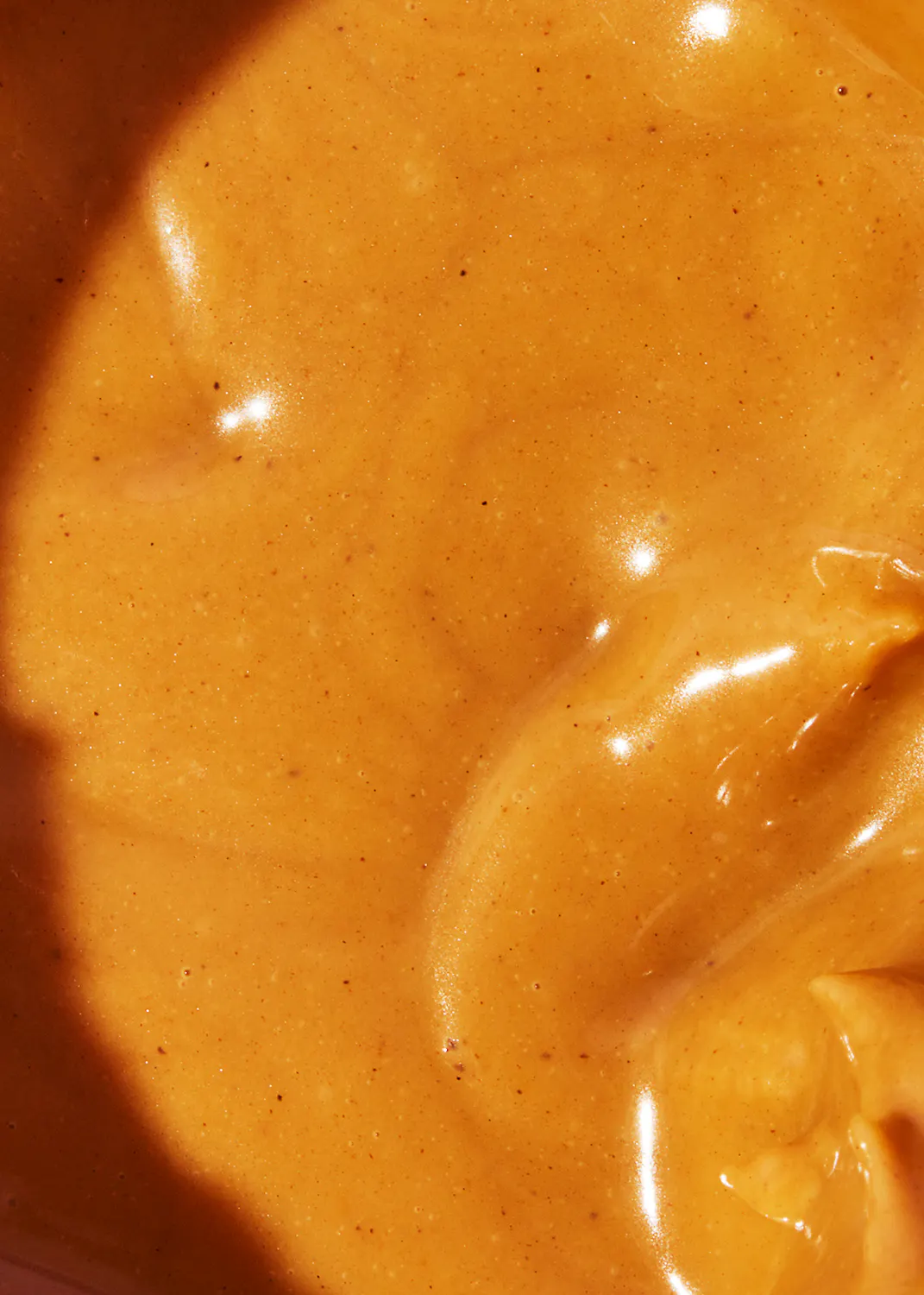 a close up of a sauce with a few small dots on it