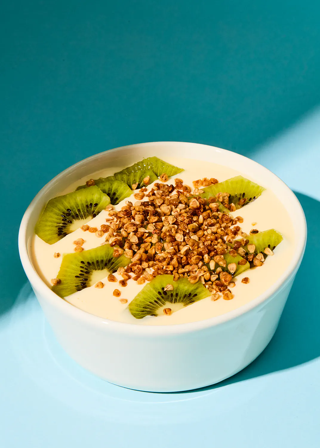 a bowl of yogurt with kiwi slices and granola on top