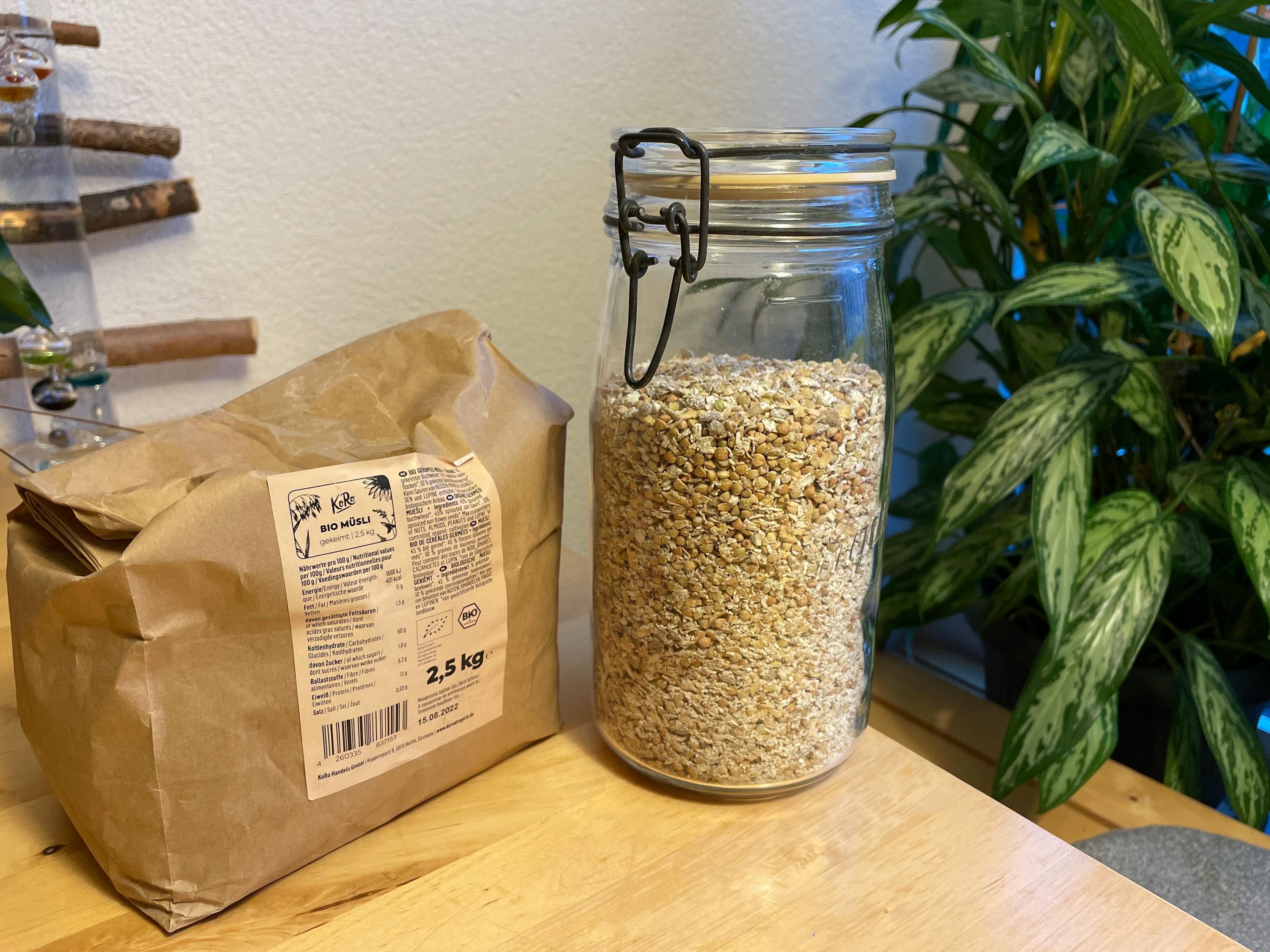 ein Glas voller Haferflocken neben einem braunen Karton