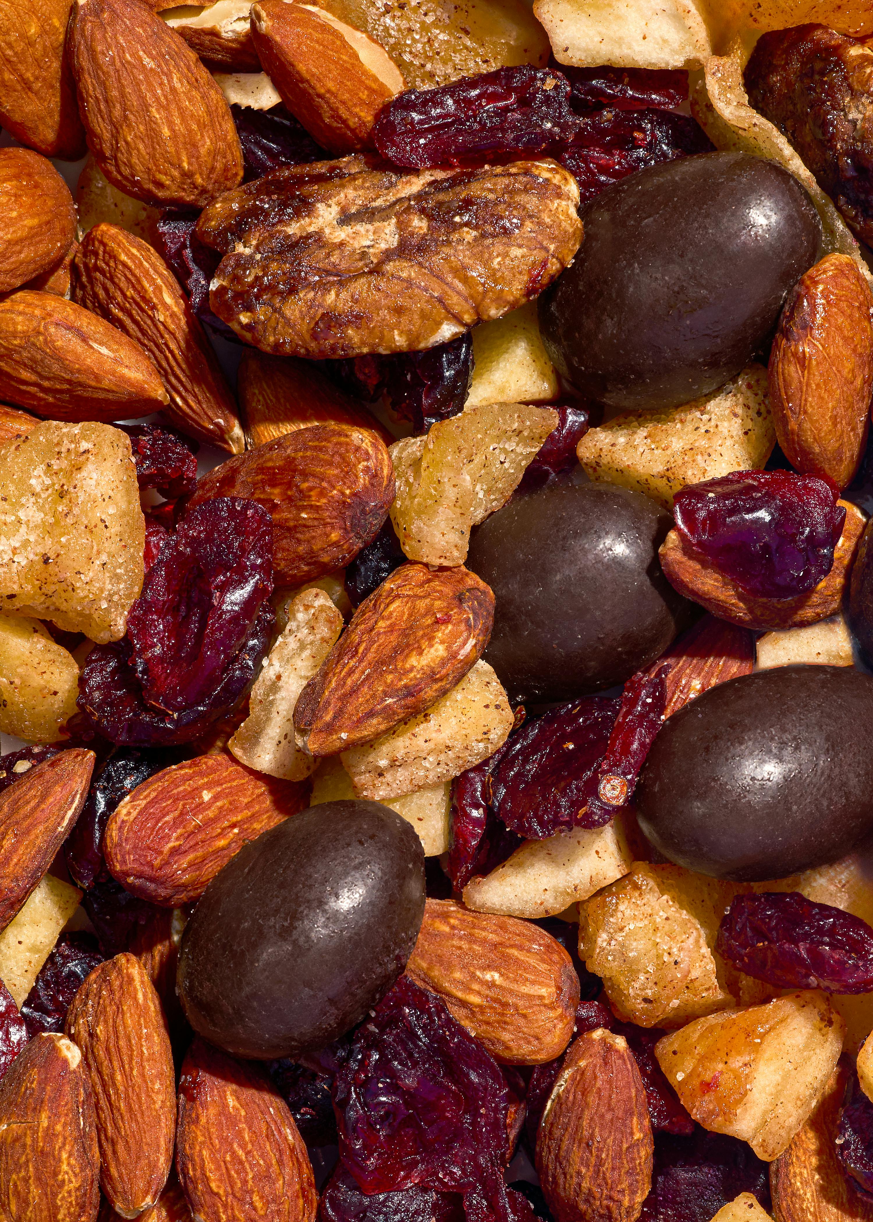 un primo piano di un mix di frutta secca e snack con mandorle, noci pecan, mirtilli rossi secchi e pezzi ricoperti di cioccolato.