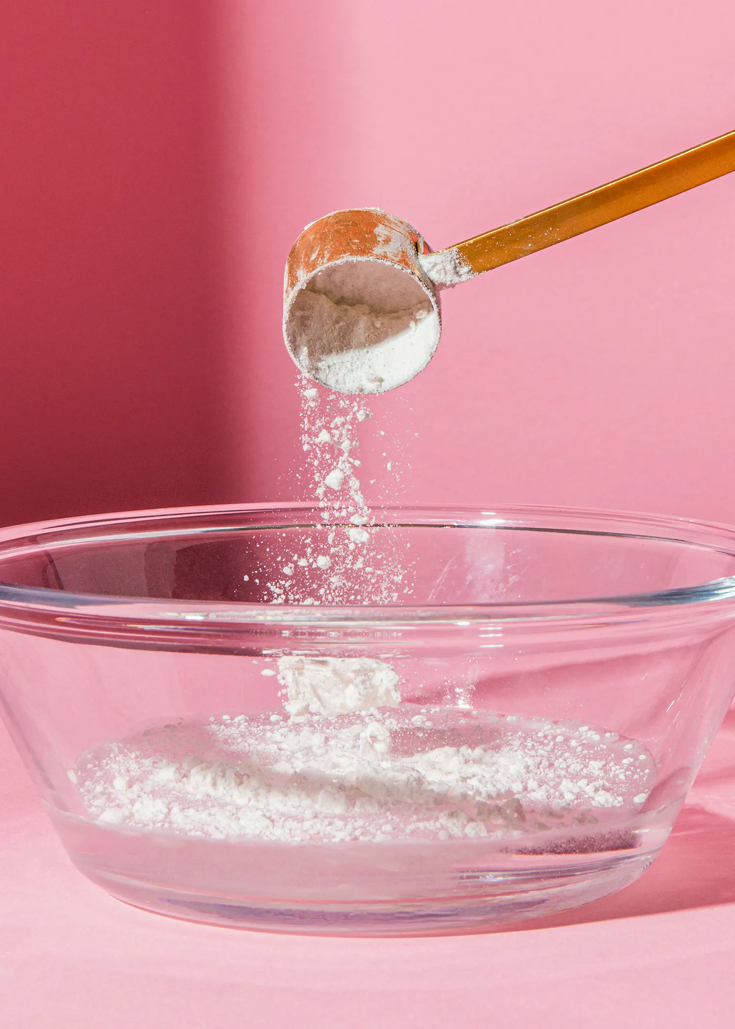 une cuillère remplie de poudre blanche est versée dans un bol en verre