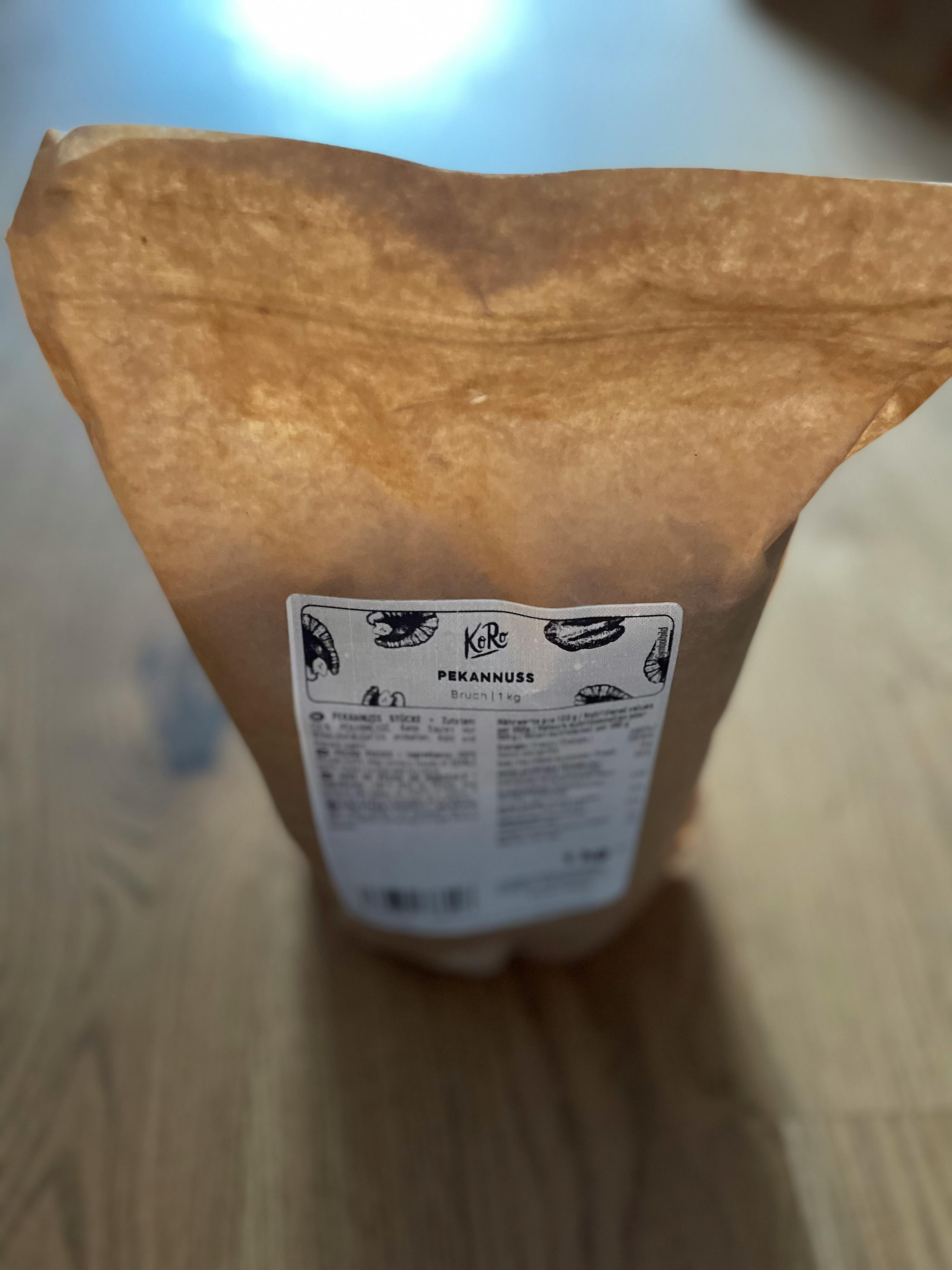 eine braune Tüte mit einer weißen Aufkleber auf der Rückseite steht auf einem Holztisch