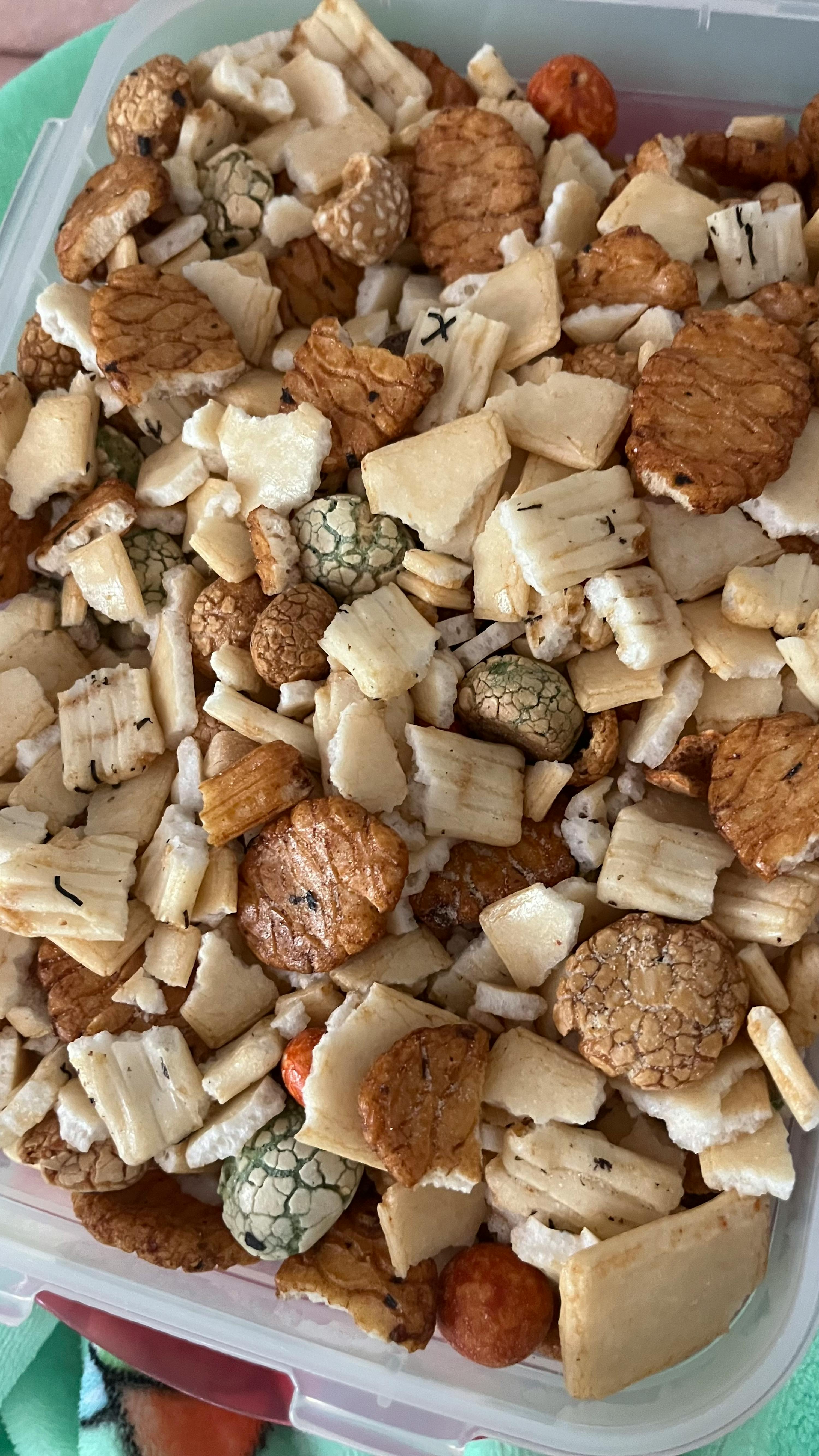 una scatola di plastica piena di vari tipi di crackers e noci