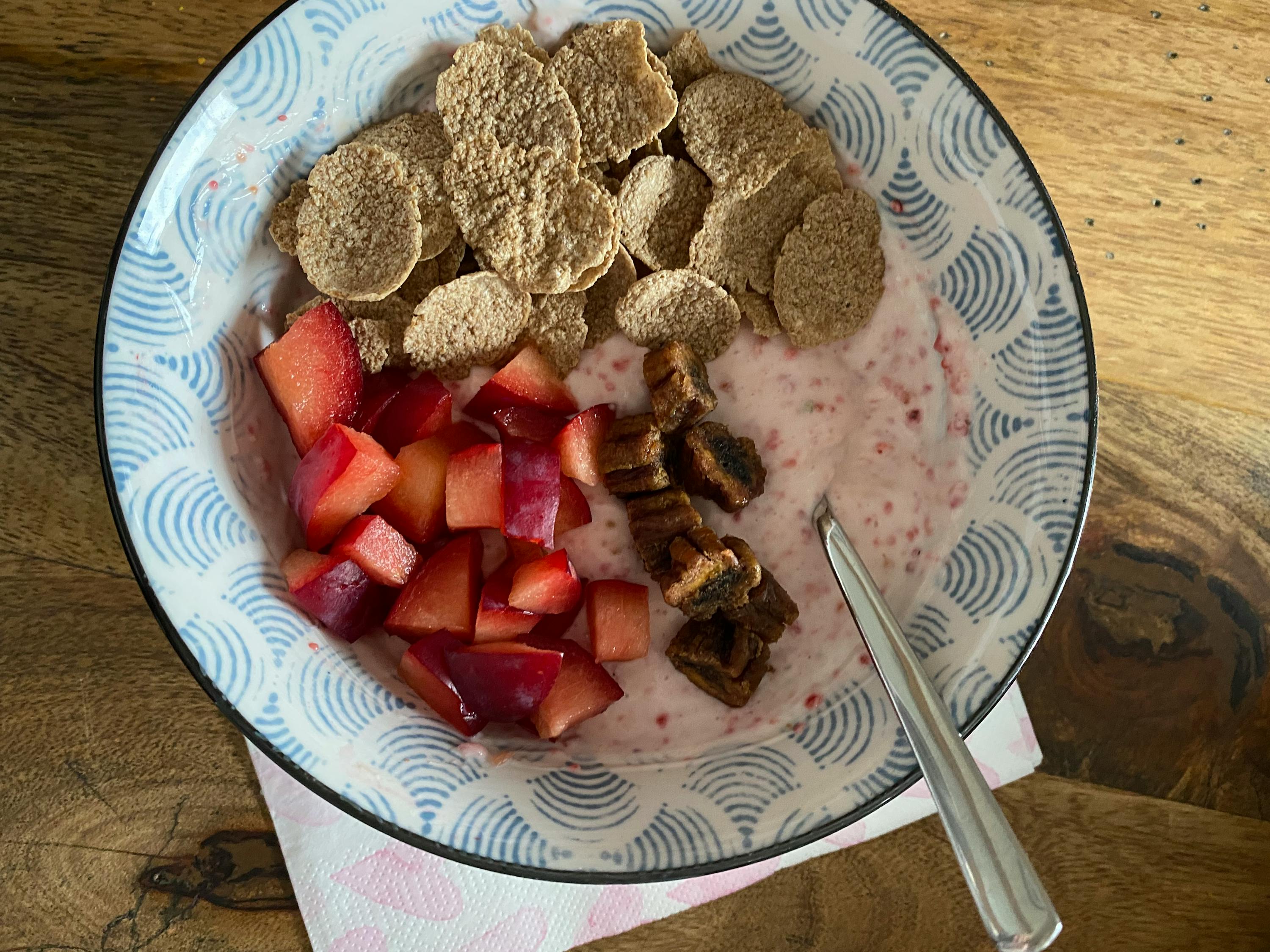 eine Schüssel mit Müsli und Obst mit einem Löffel darin