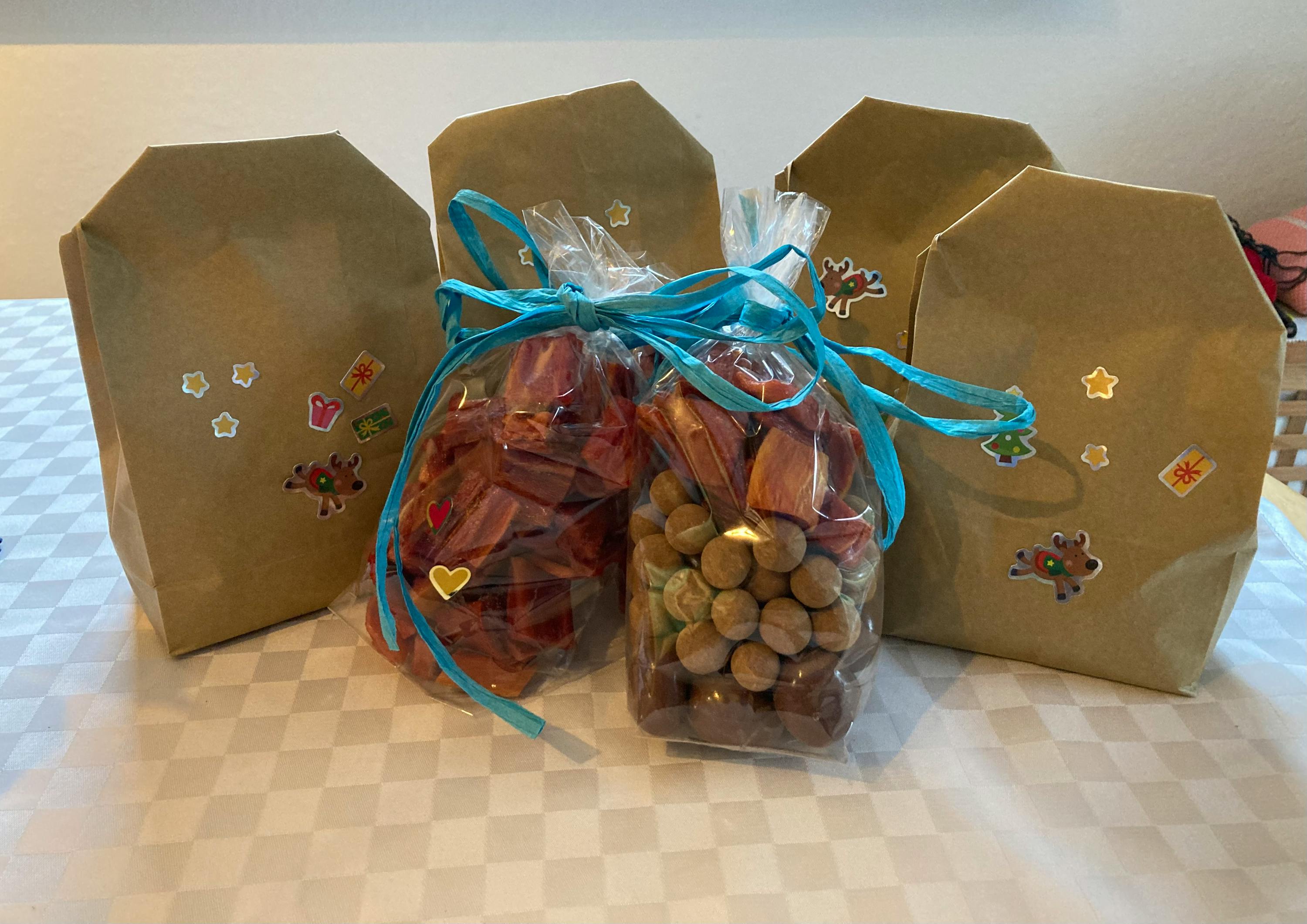 drei braune Taschen mit Leckereien sitzen auf einem karierten Tisch