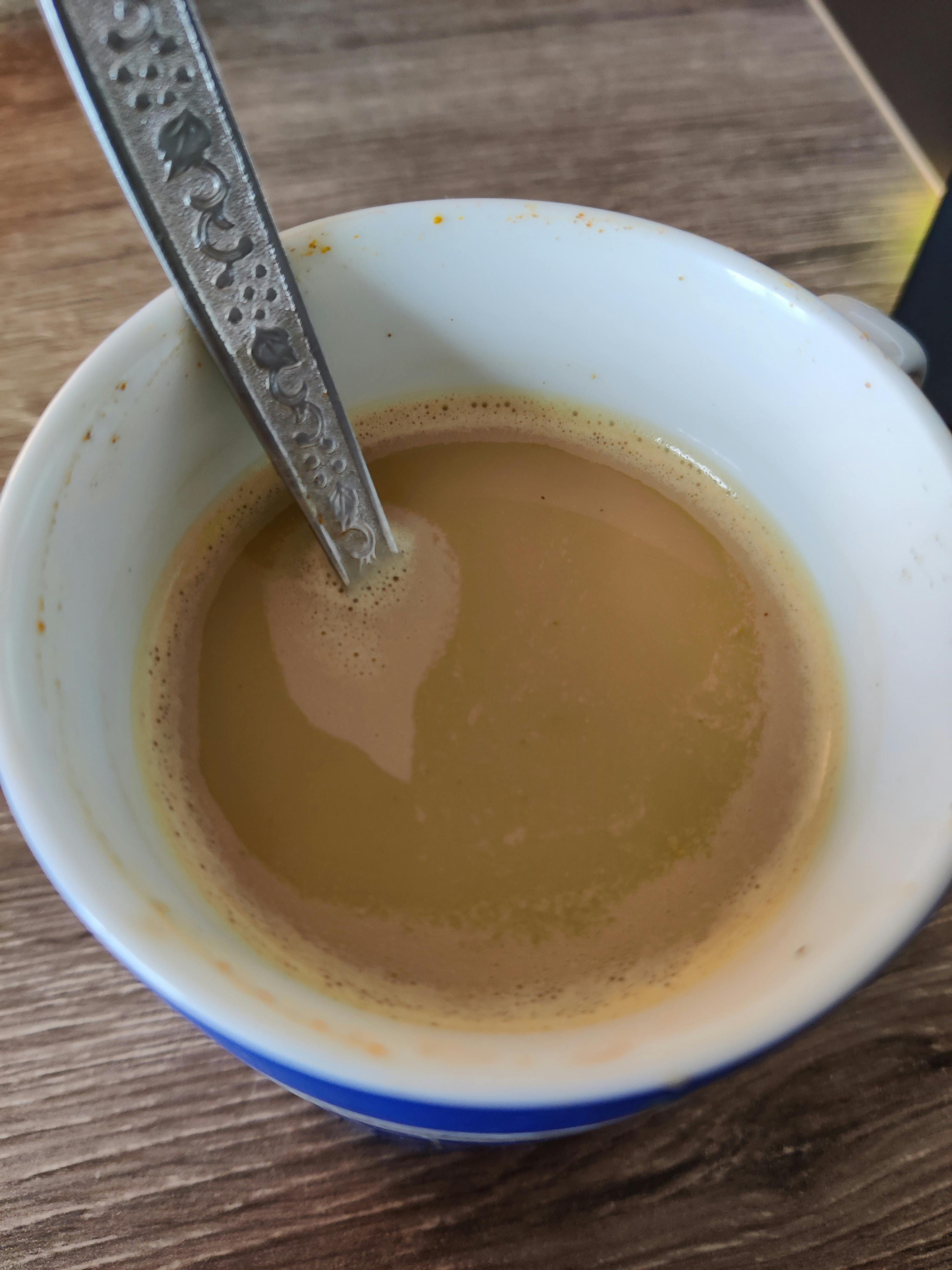 eine weiße und blaue Tasse Kaffee mit einem Löffel darin