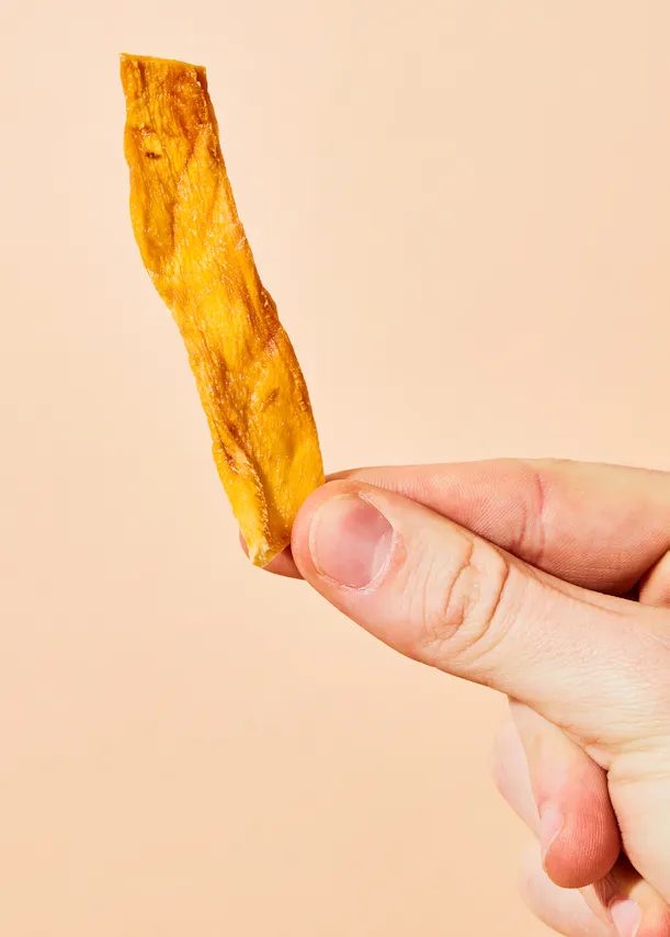 eine Person hält einen Stück getrockneten Obst in der Hand