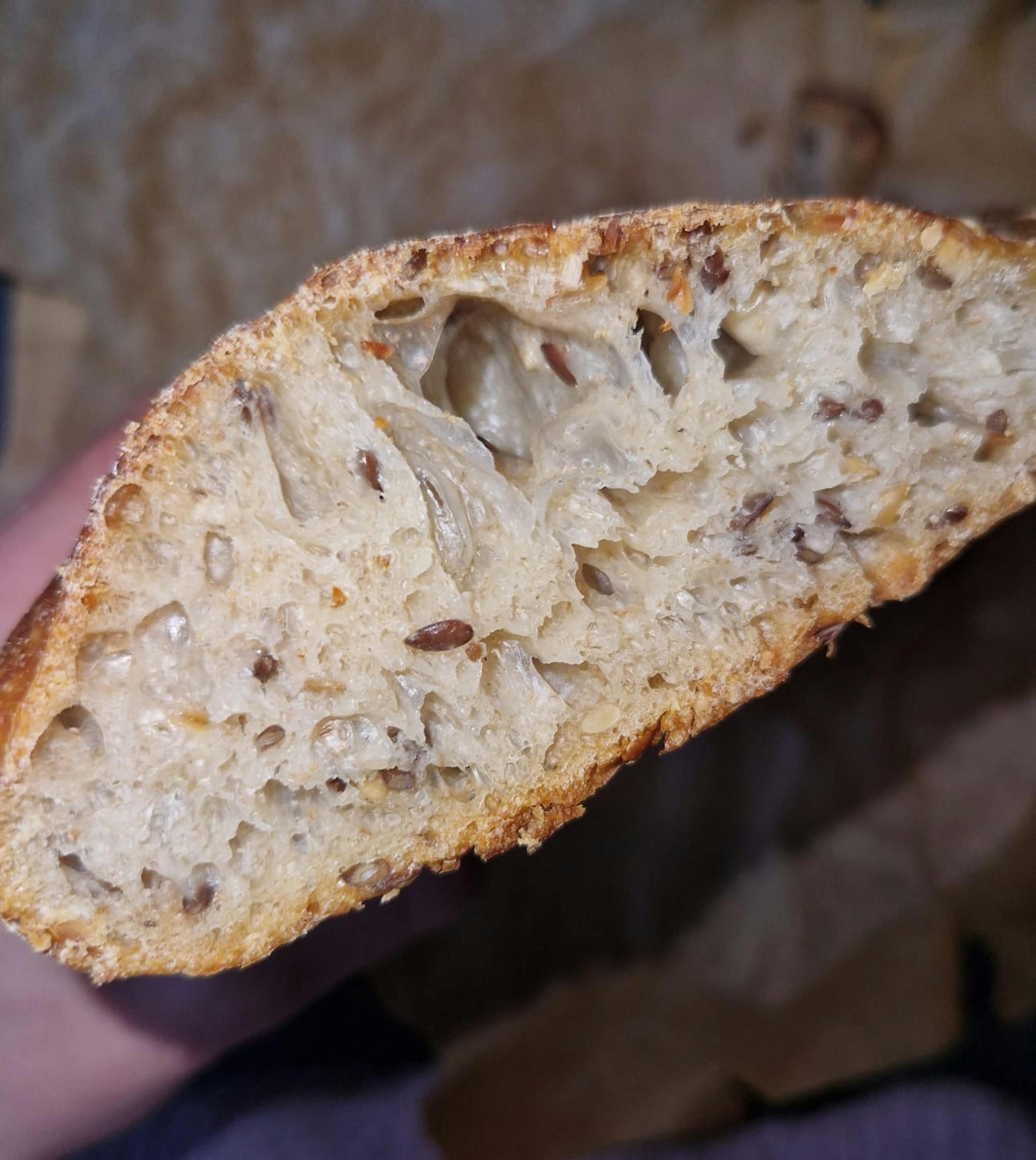 a person is holding a loaf of bread with seeds in it