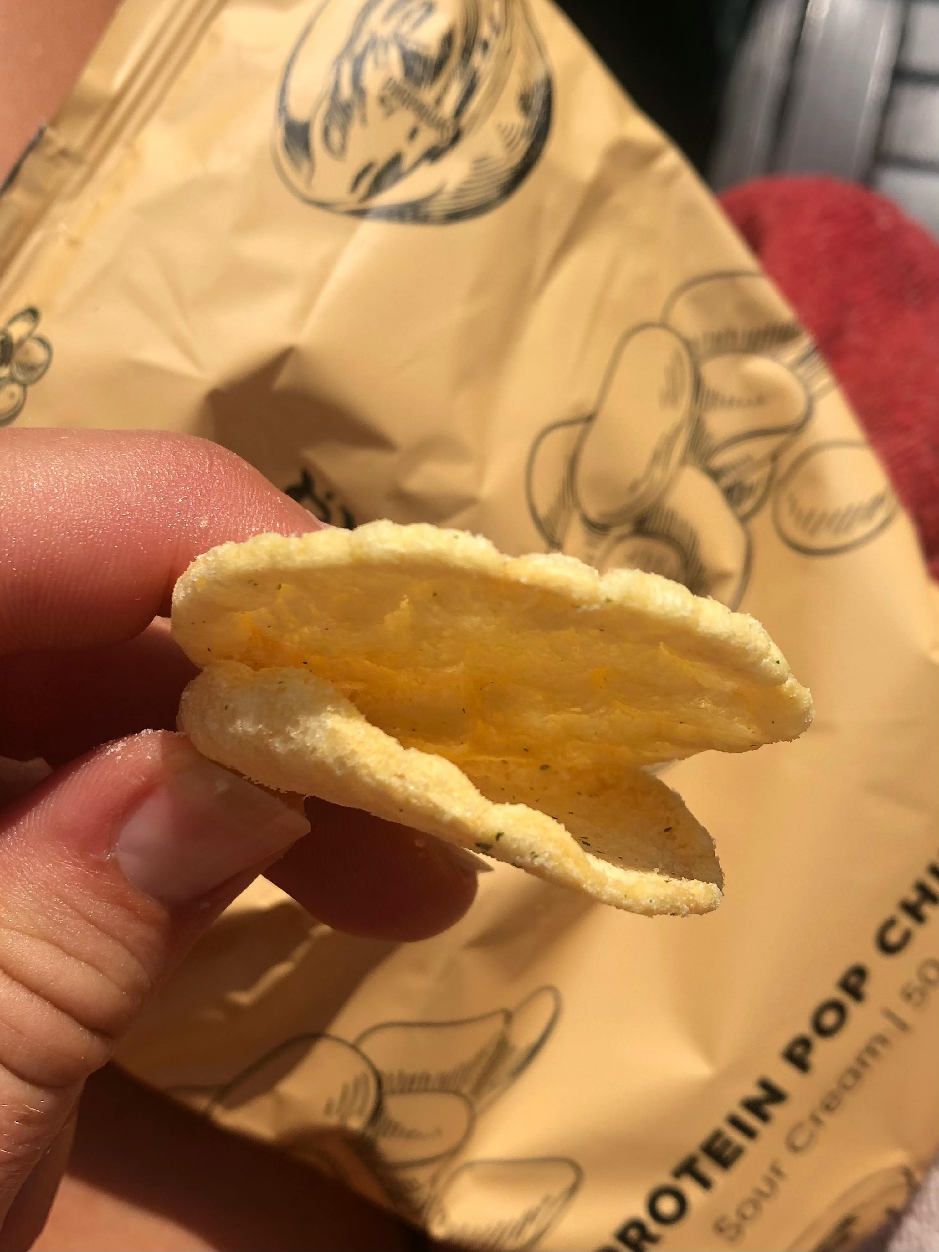 a person is holding a bag of protein popcorn chips