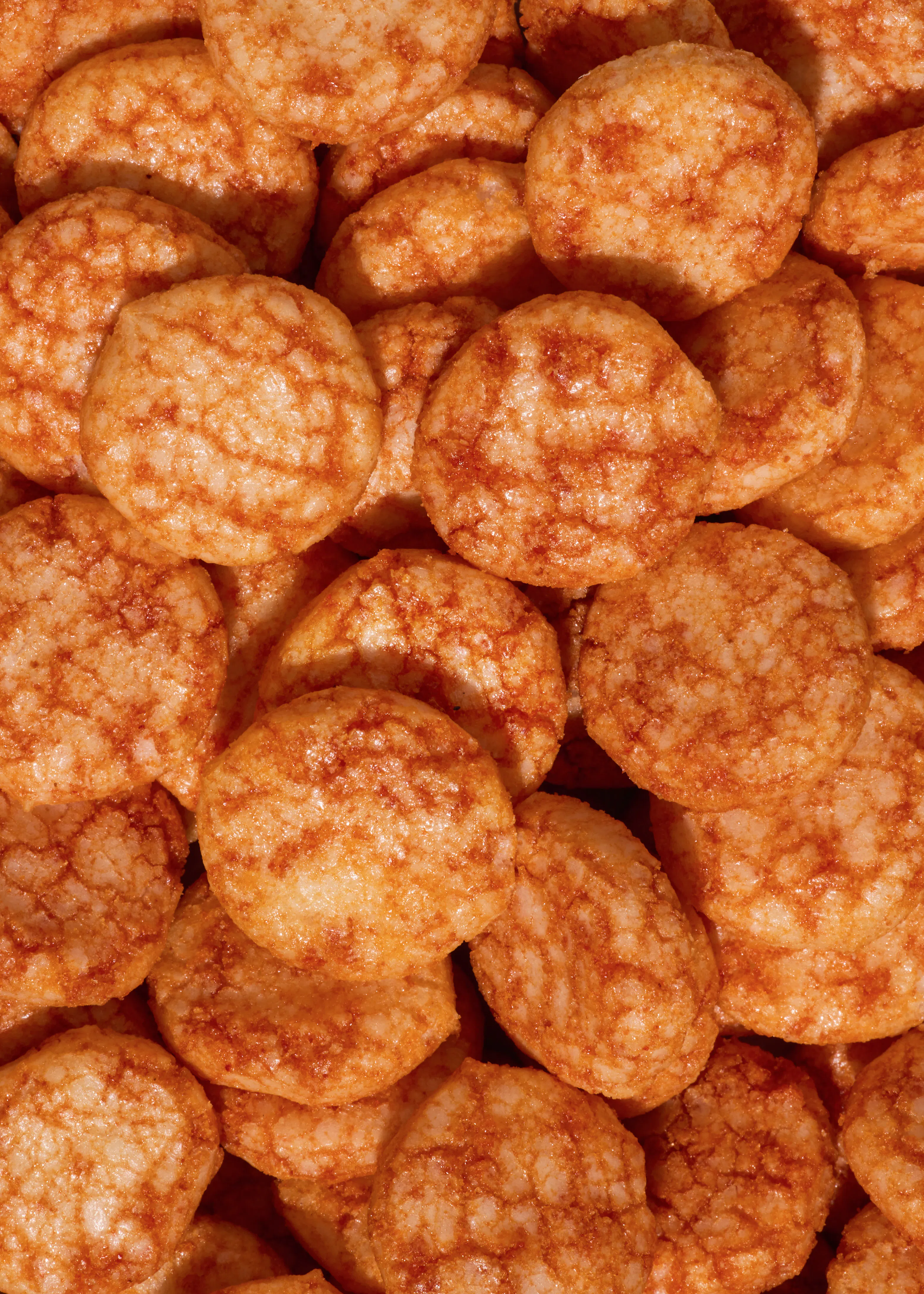 gros plan sur une pile de craquelins de riz ronds et dorés, présentant une surface légèrement texturée.