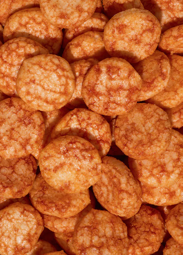 gros plan sur une pile de craquelins de riz ronds et dorés, présentant une surface légèrement texturée.
