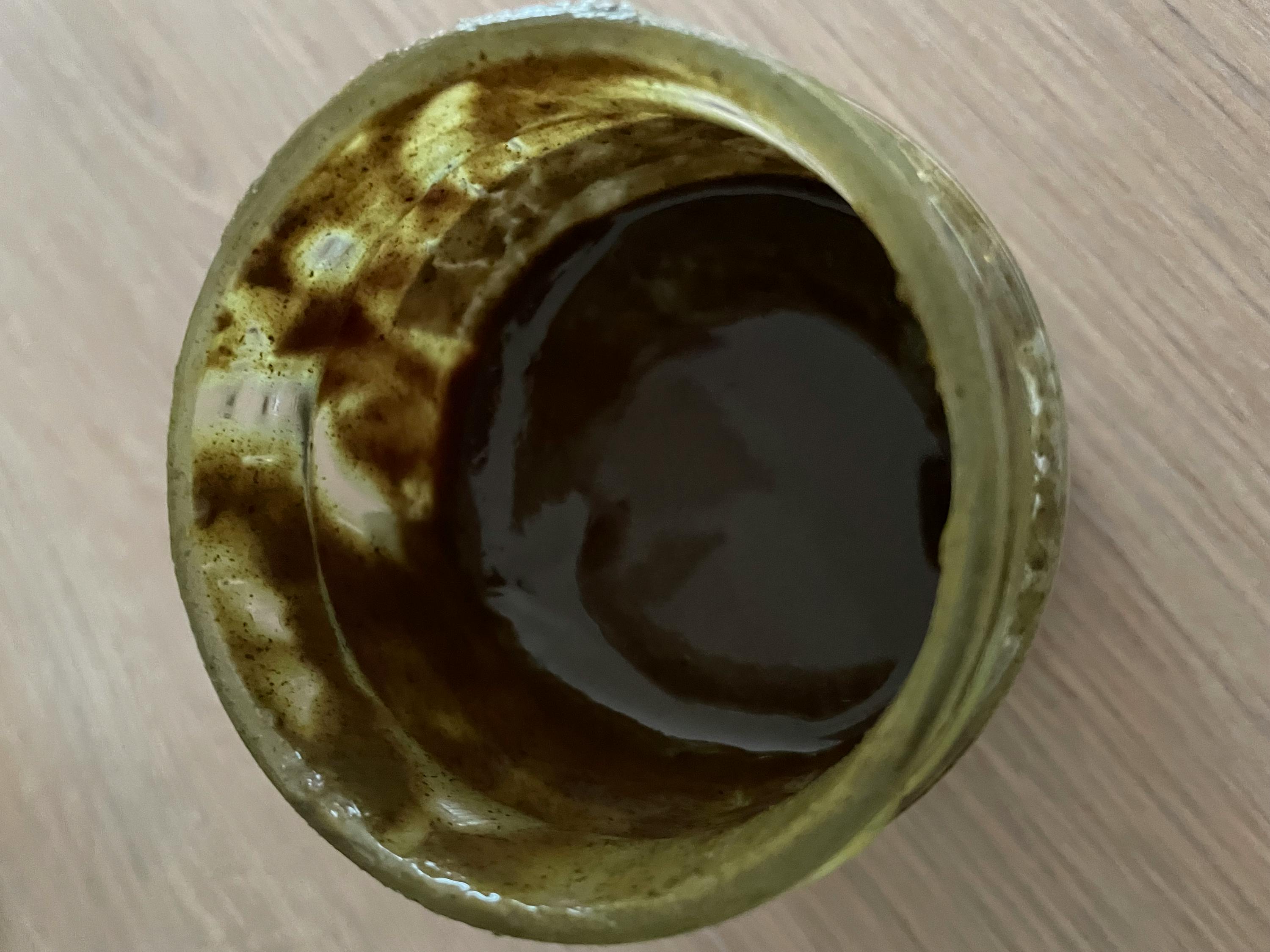 a green jar filled with brown liquid on a table