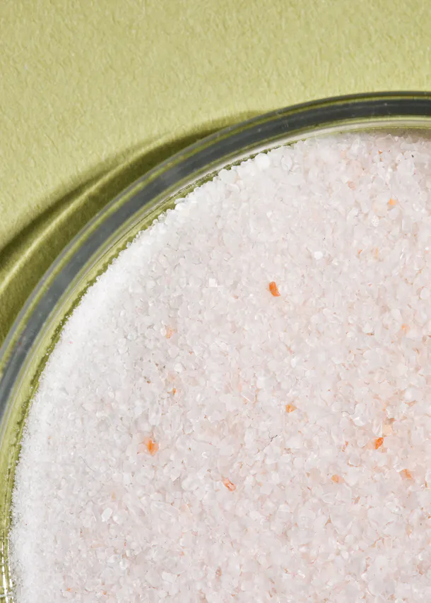 un gros plan d' un bol en verre rempli de sel rose